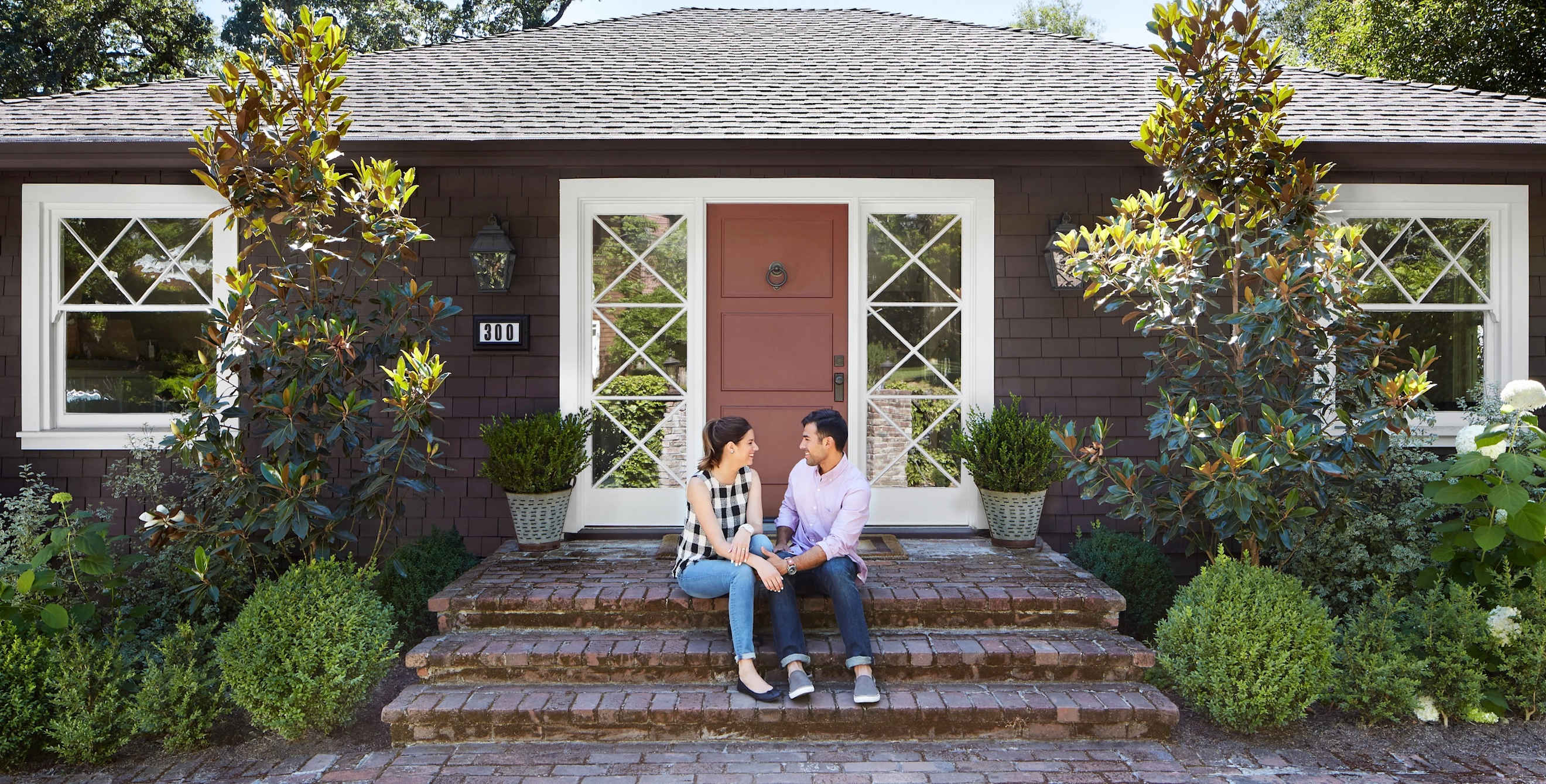 young couple sitting on brick steps outside their new home
