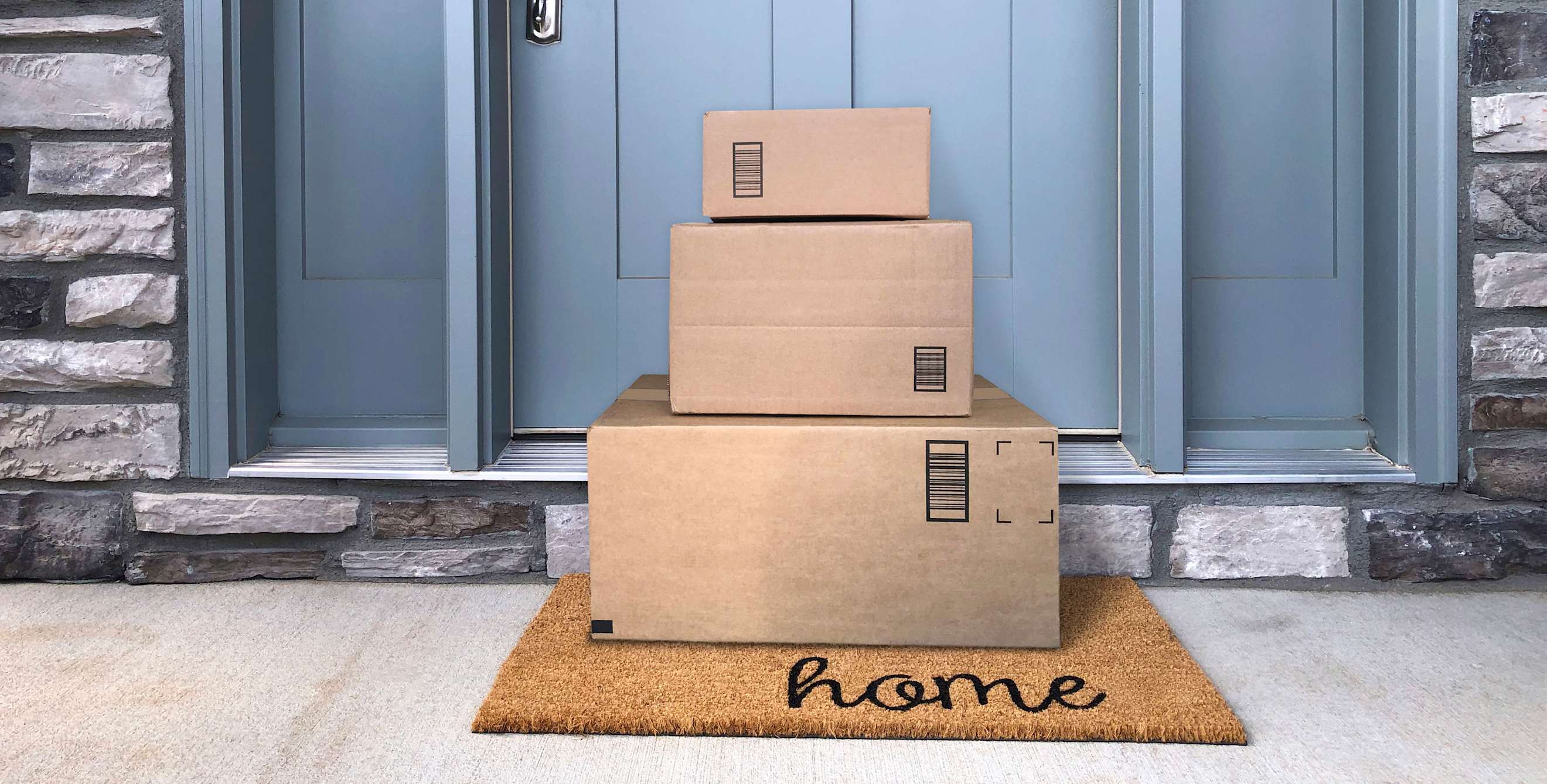 three packages stacked on mat at doorstep
