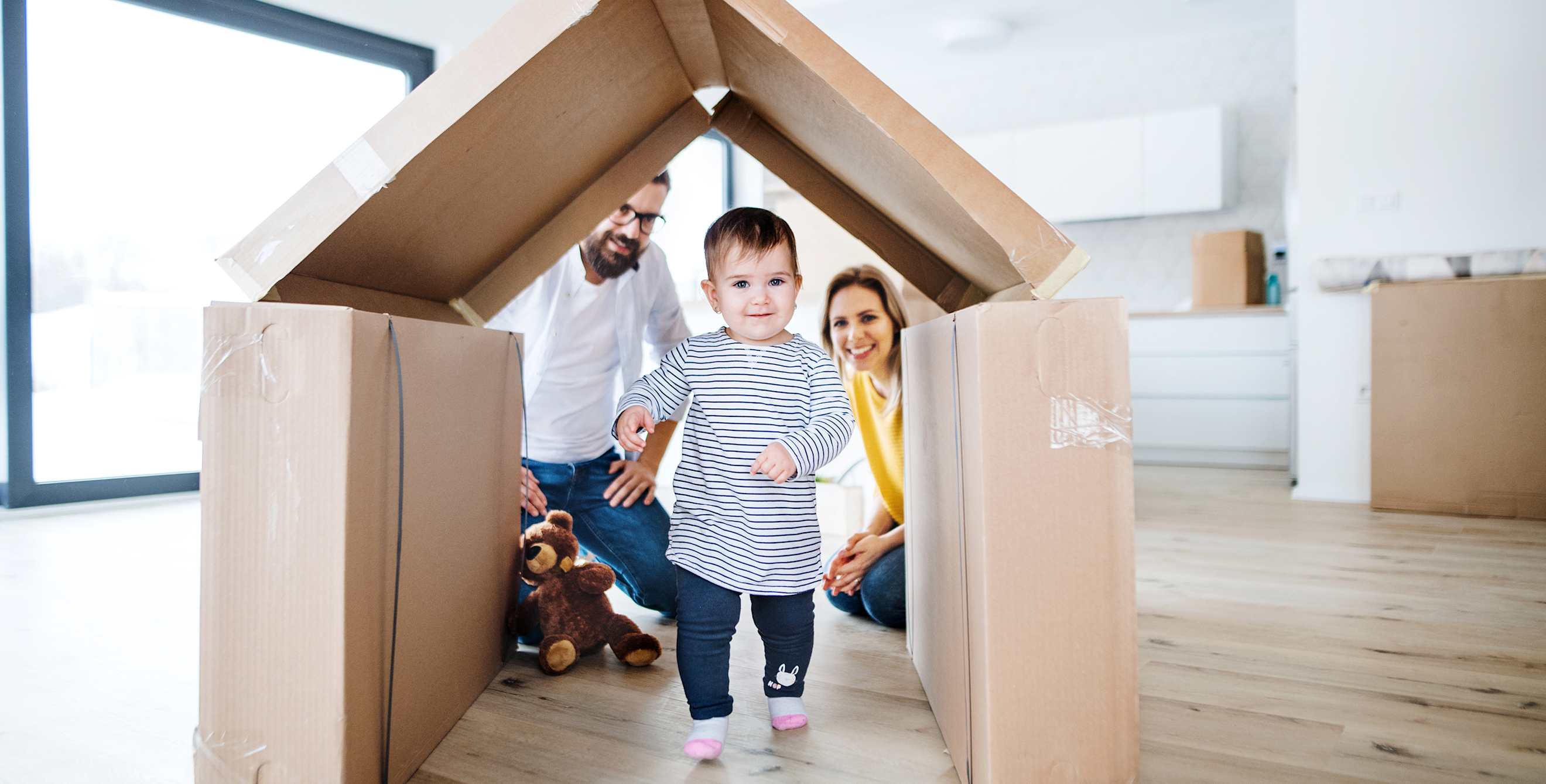 A toddler walks through a house made out of boxes.