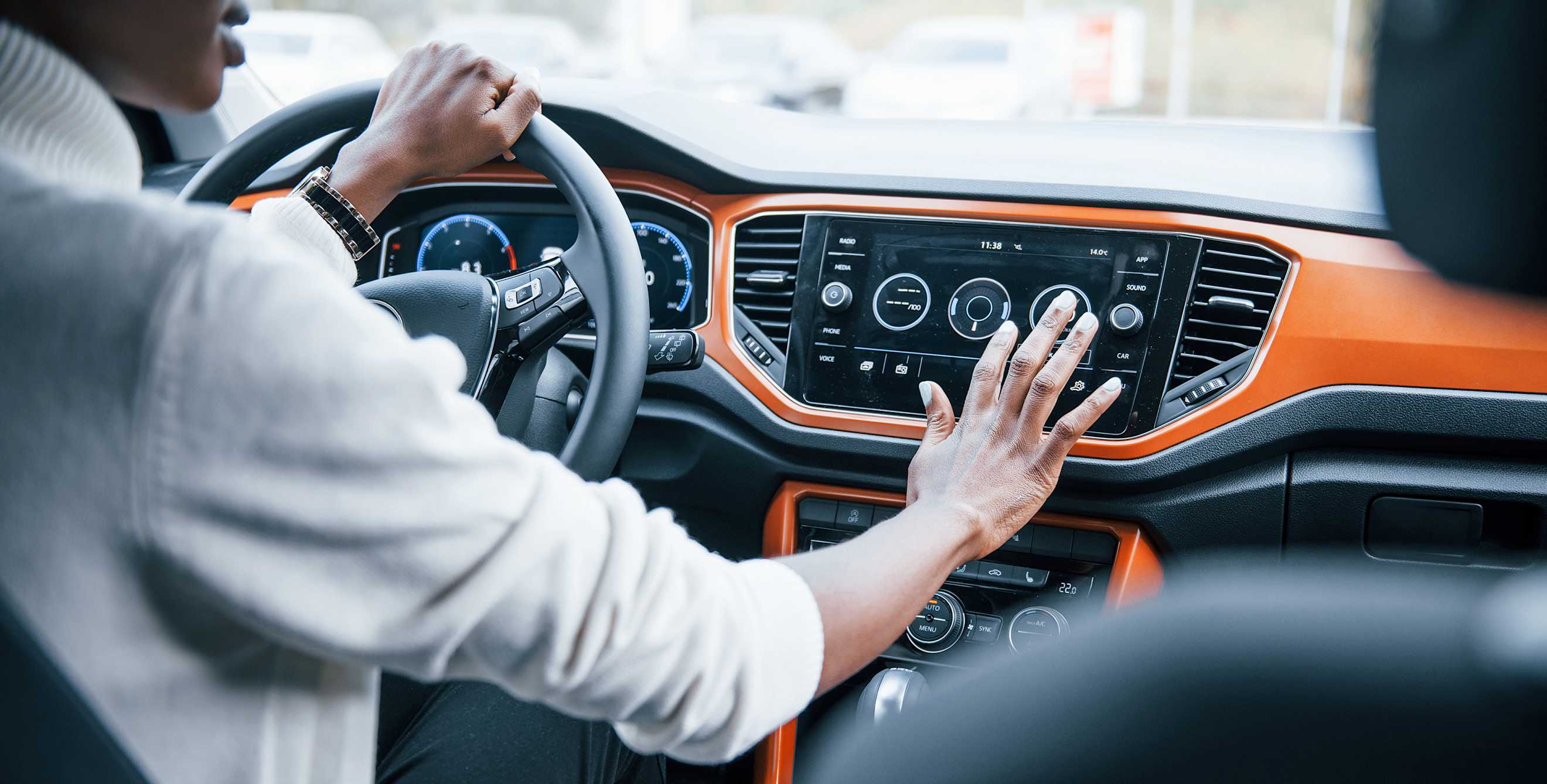 A woman makes adjustments on a car dashboard touchscreen before driving.