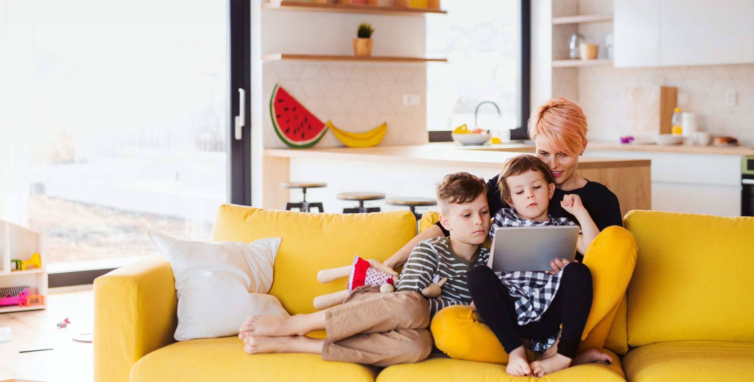 A mother sits on the couch with her two children.