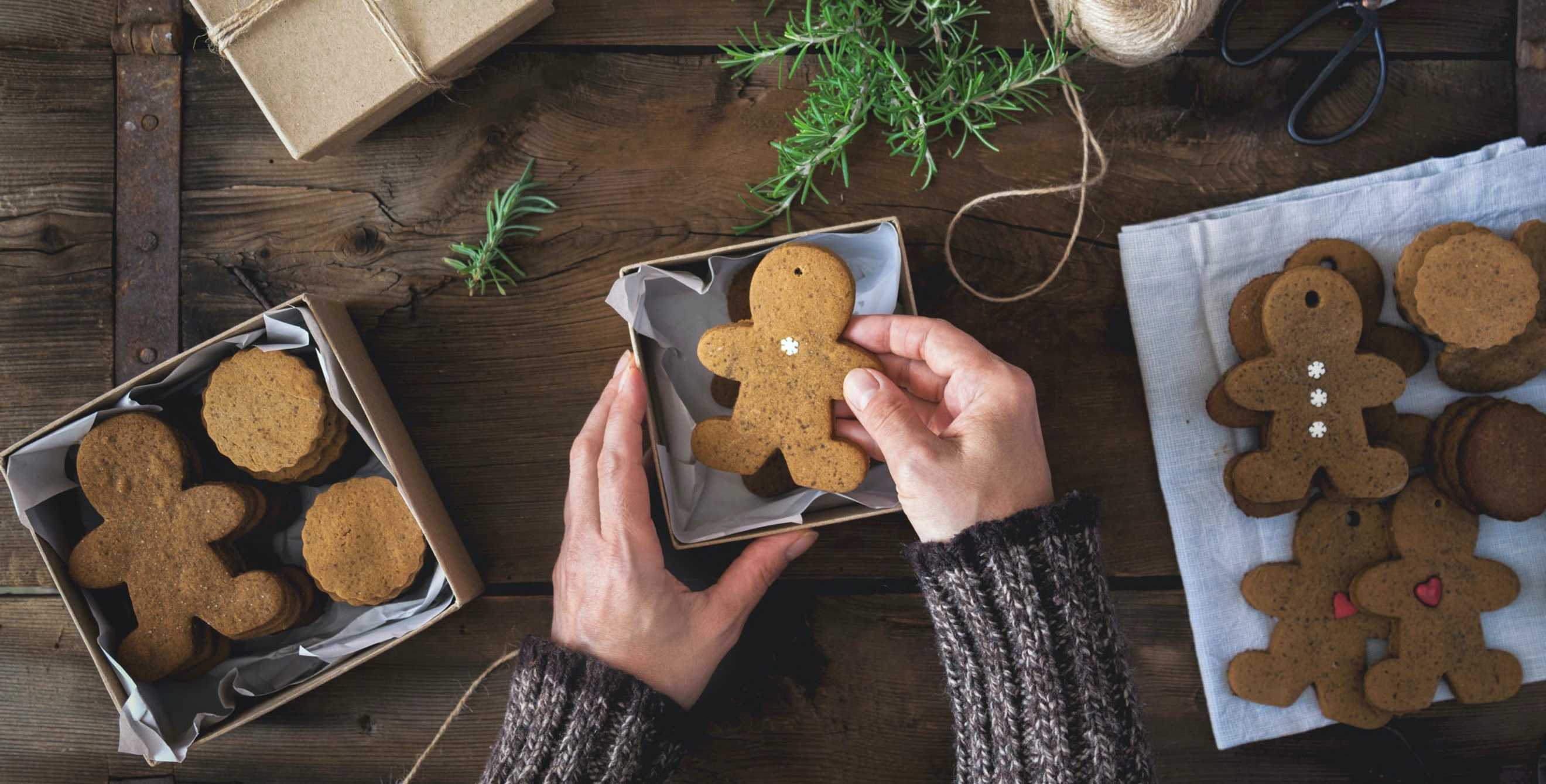 hands prepare gift boxes filled with gingerbread men