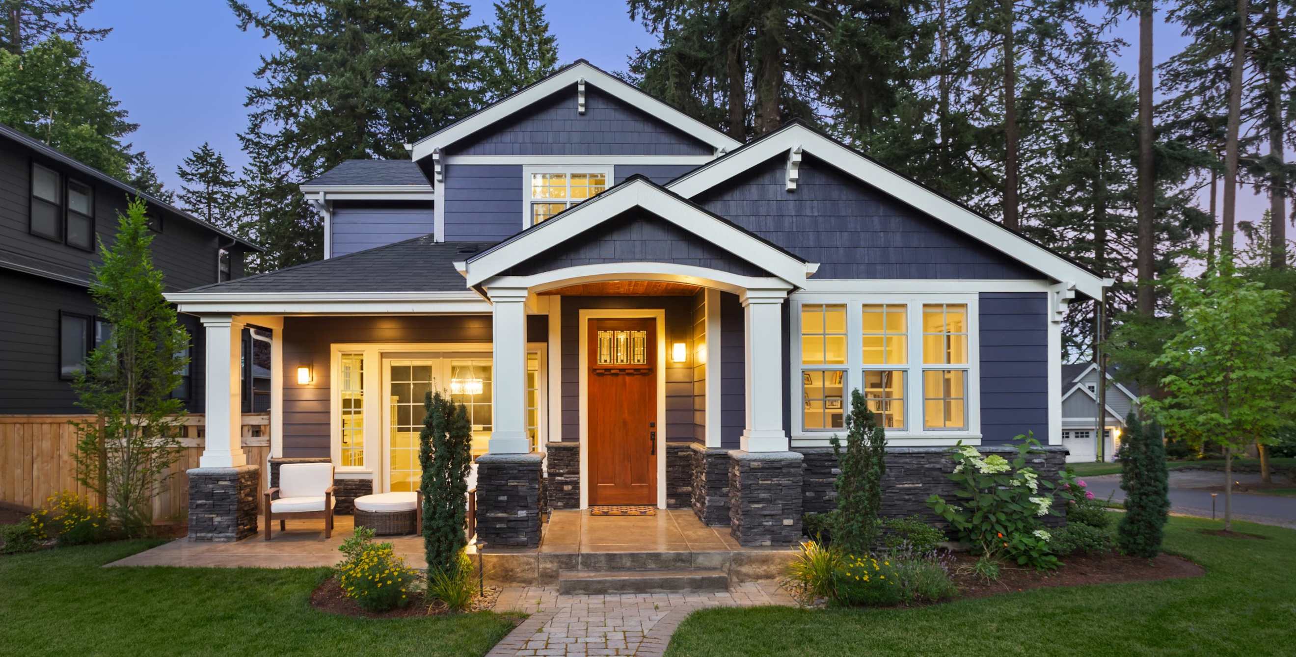 A contemporary blue home lit up at sunset.
