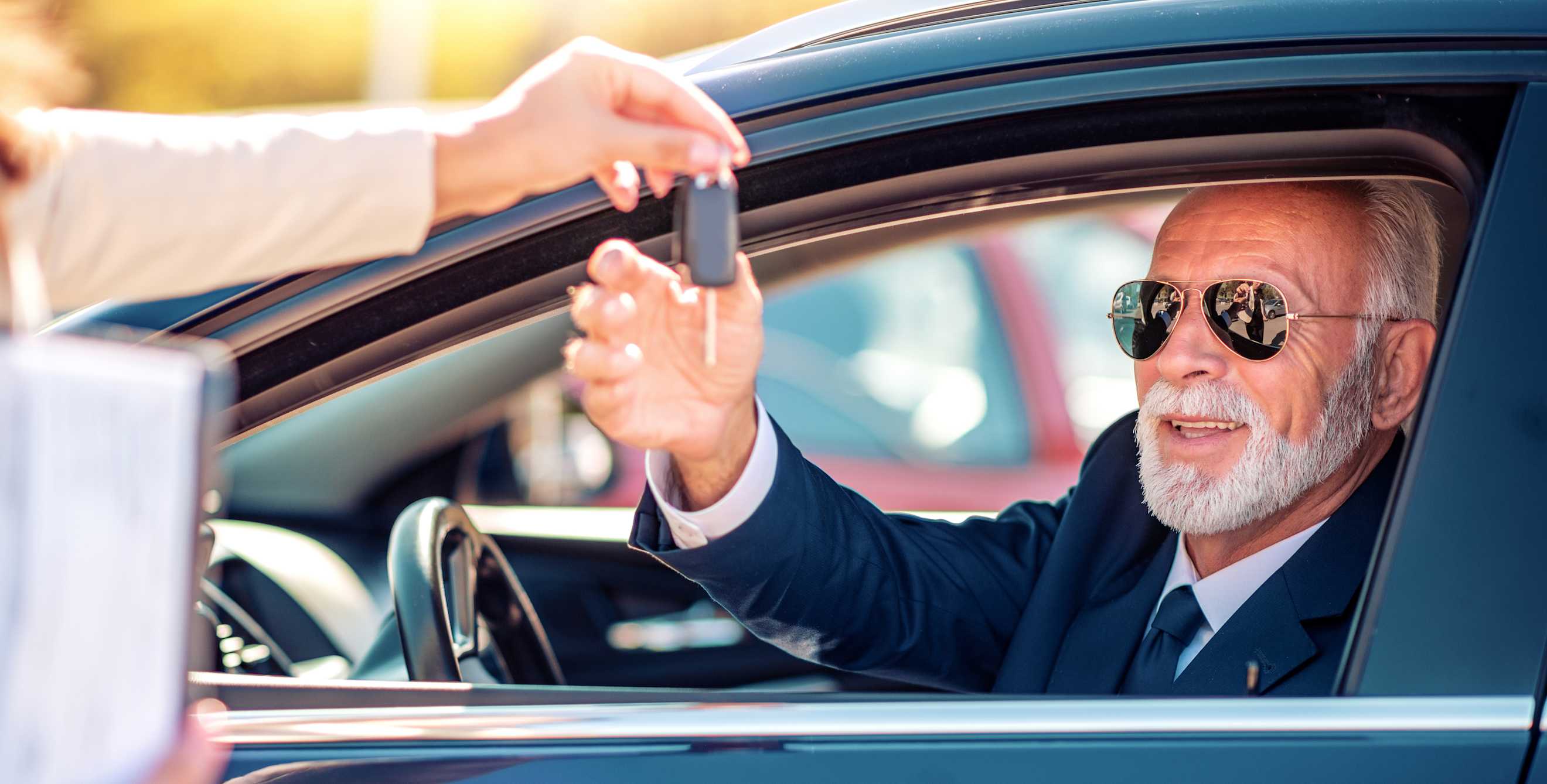 A senior man is handed the key to his new car.