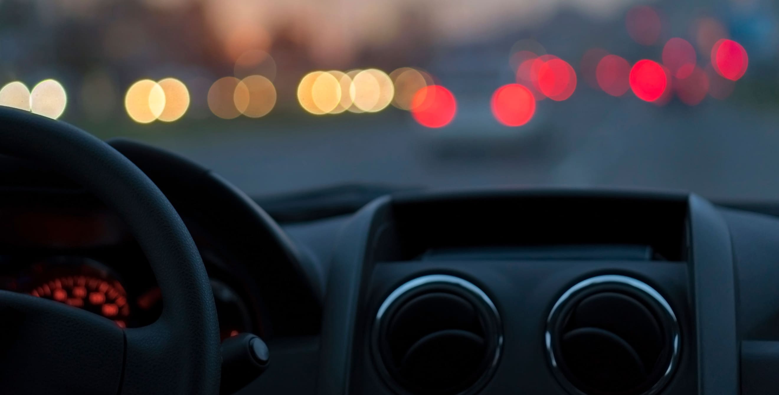 Headlights and brake lights shine through a windshield.