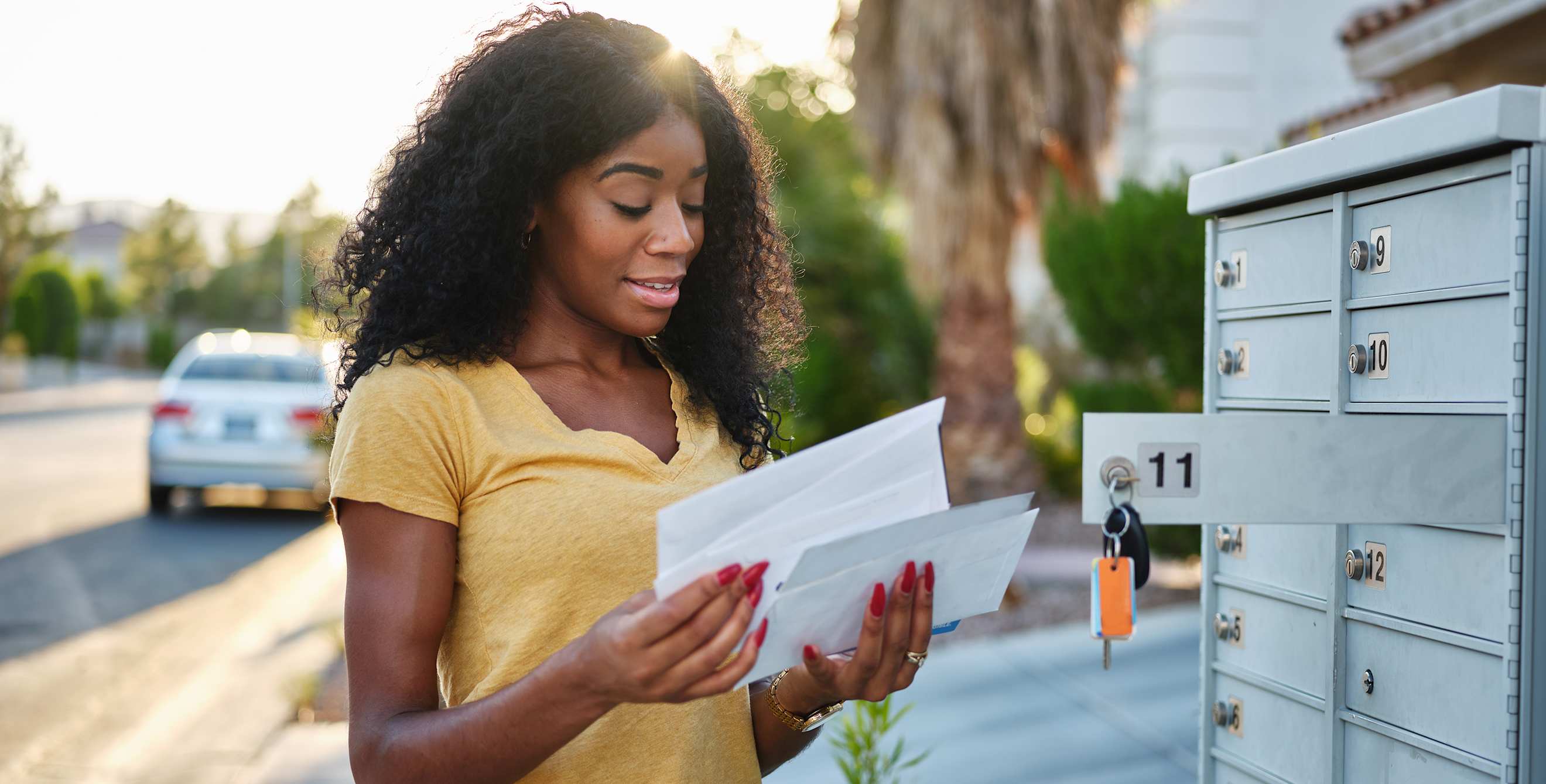 A woman opens her mail at the mailbox.