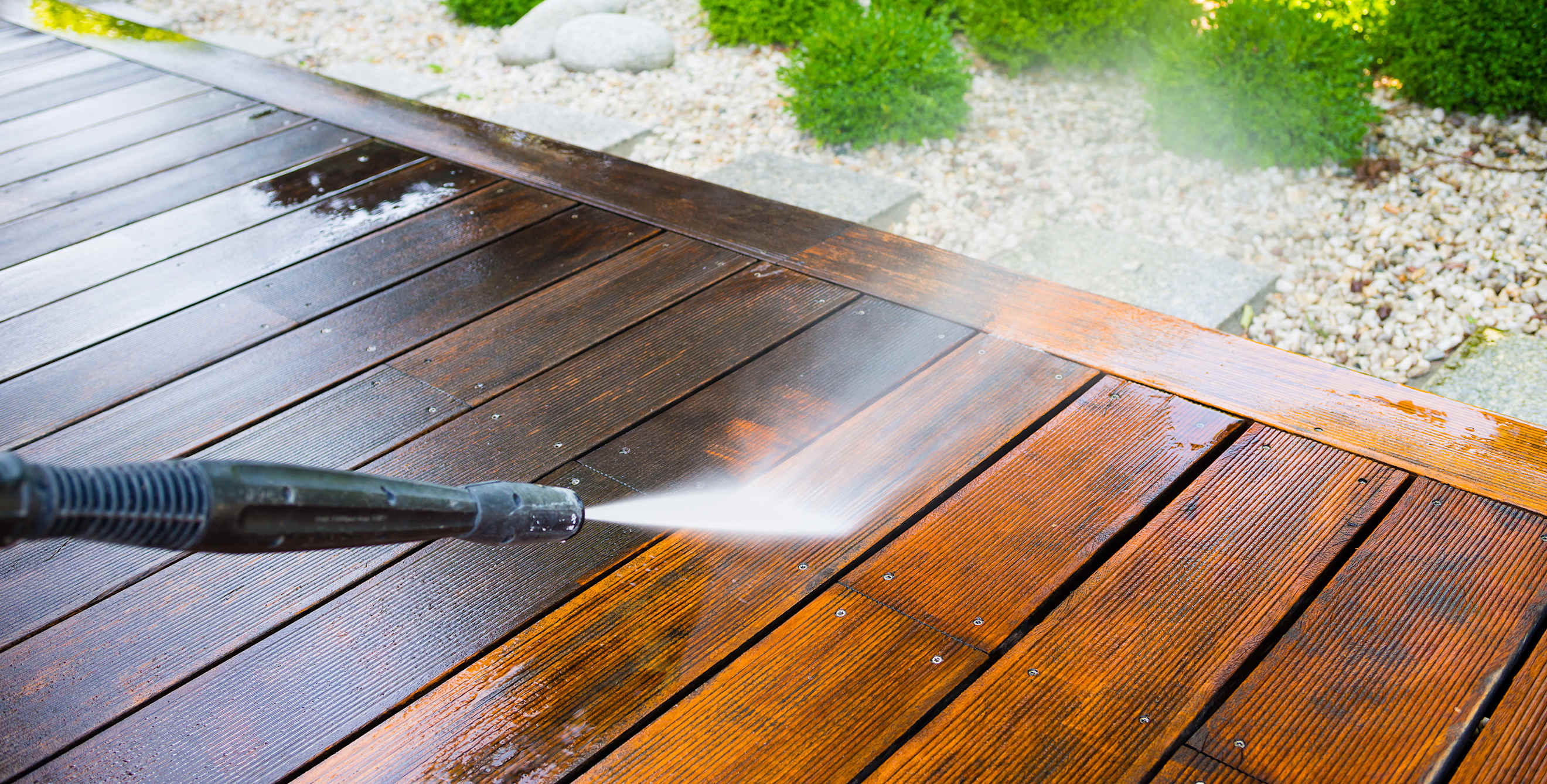 A homeowner pressure washes their deck.