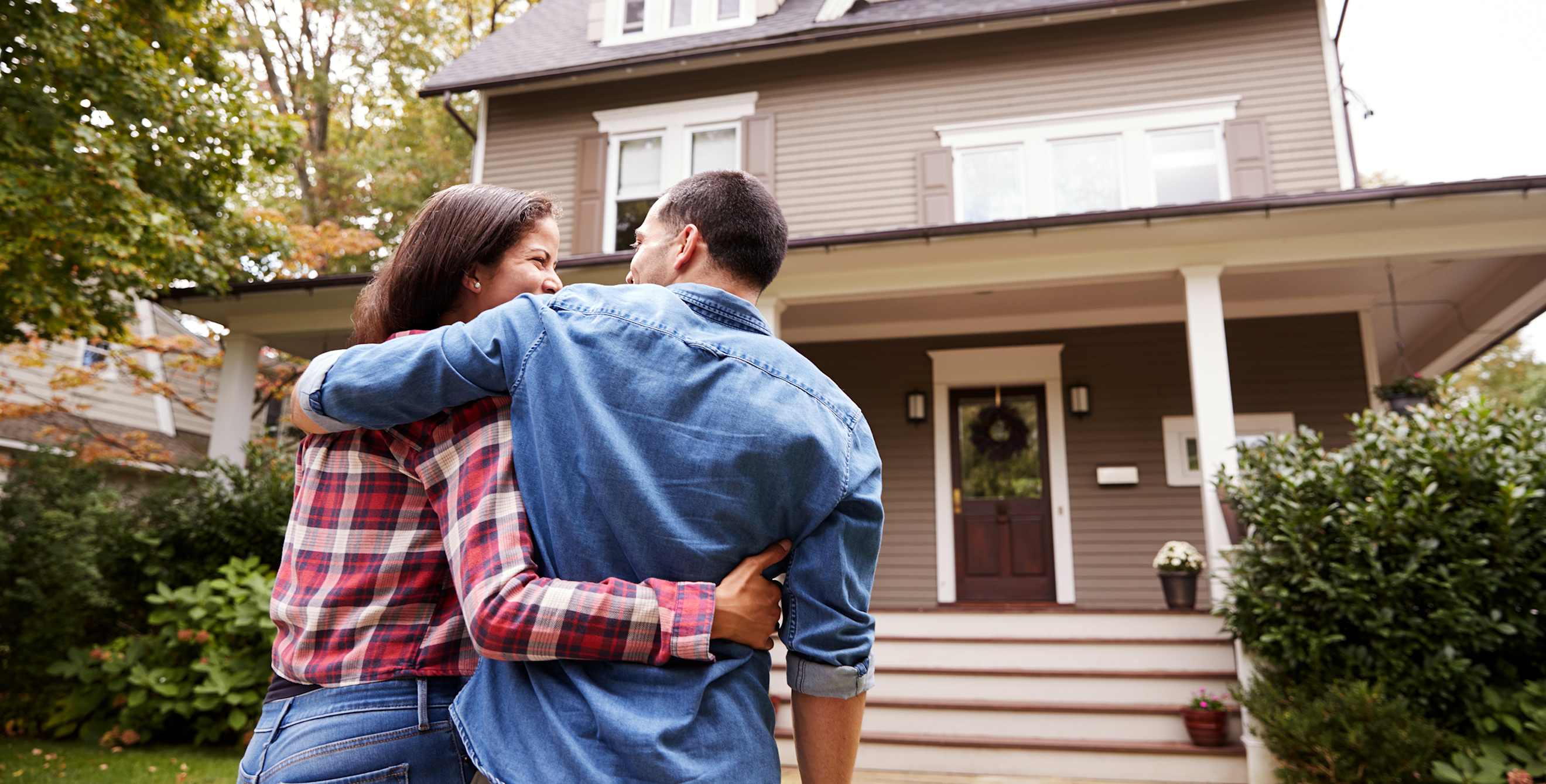 New home buyers stand in front of their house.