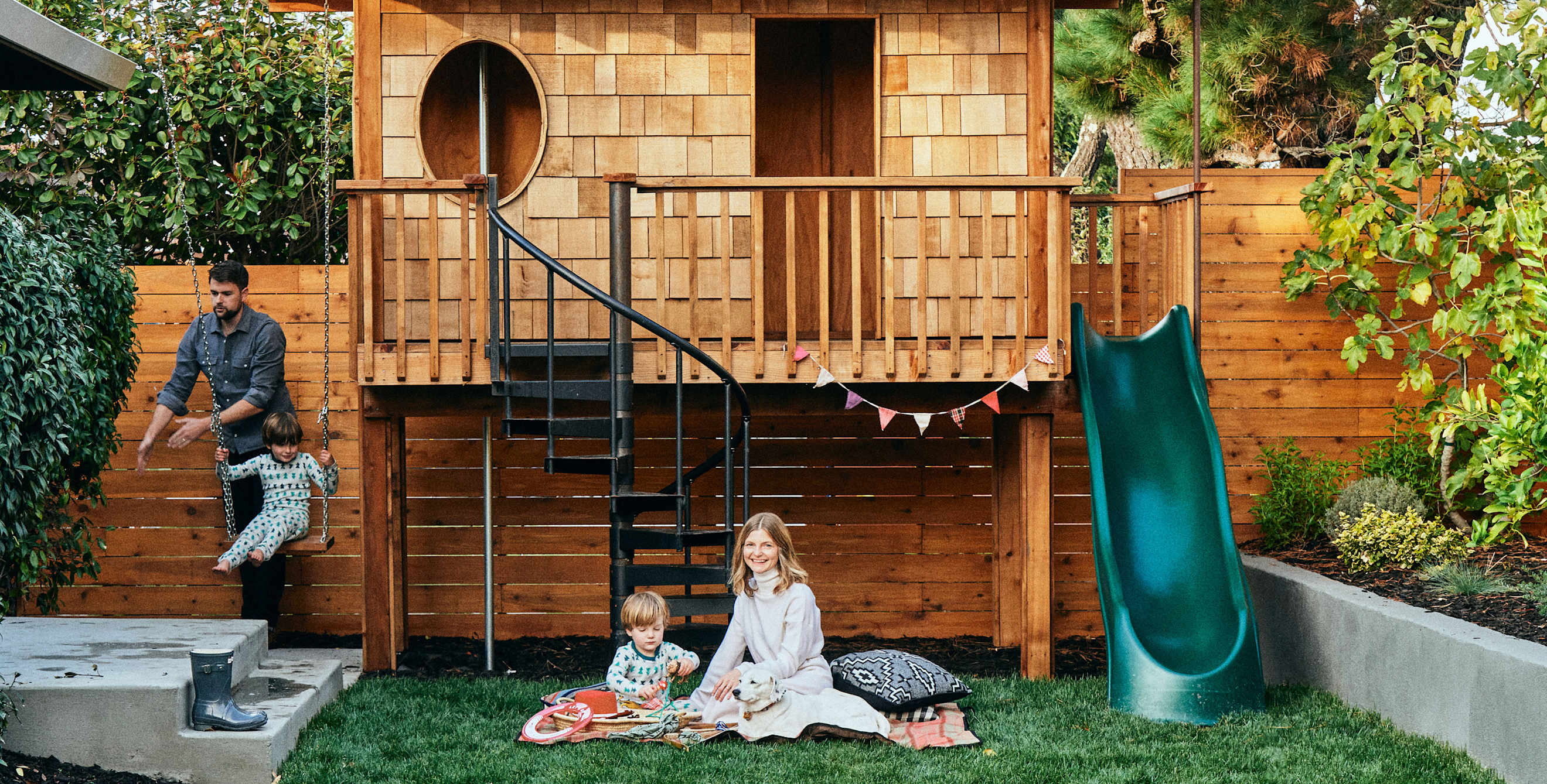 A family plays outside on their play structure.