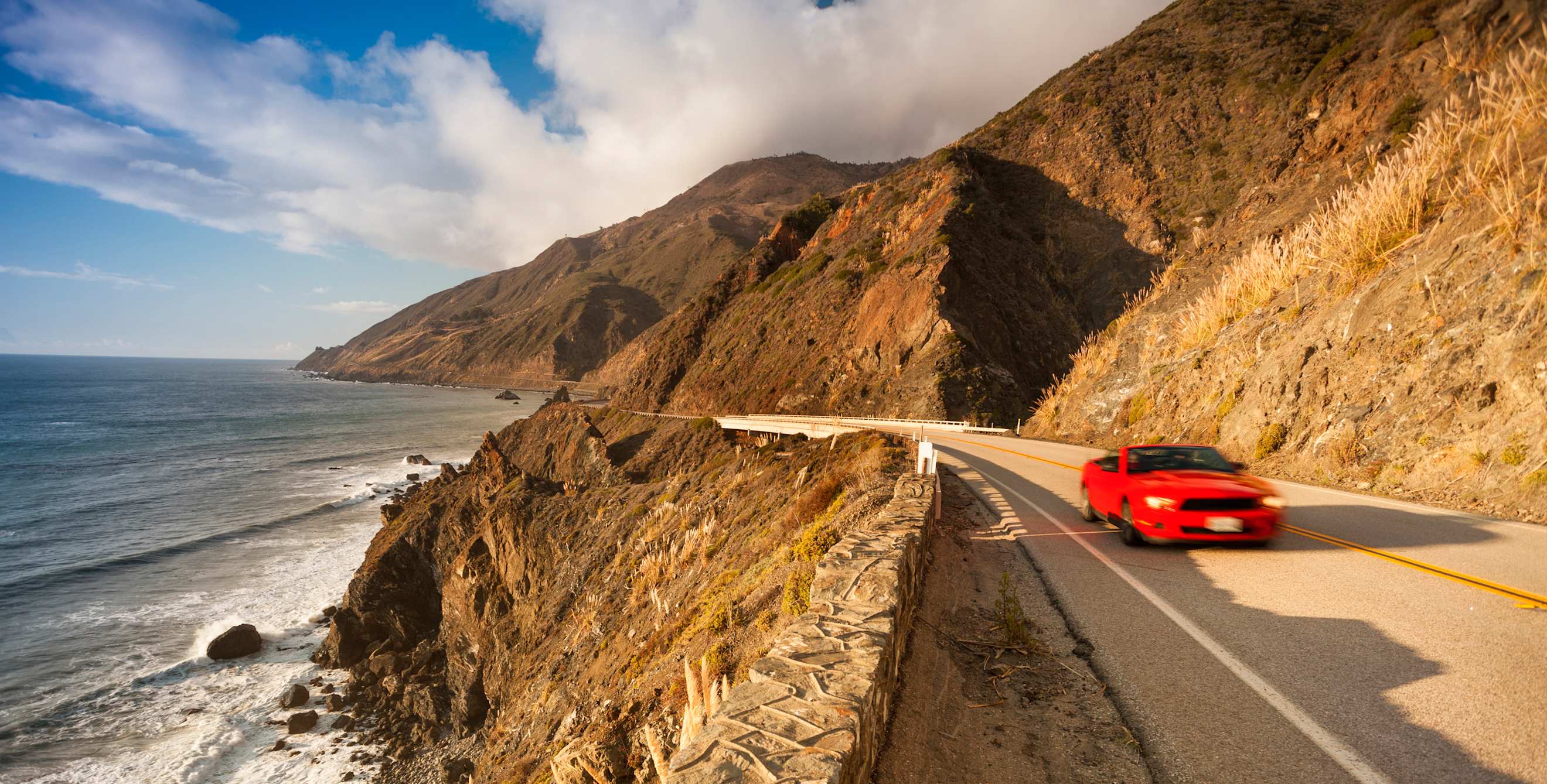 A convertible drives along California's Highway 1 near Big Sur.
