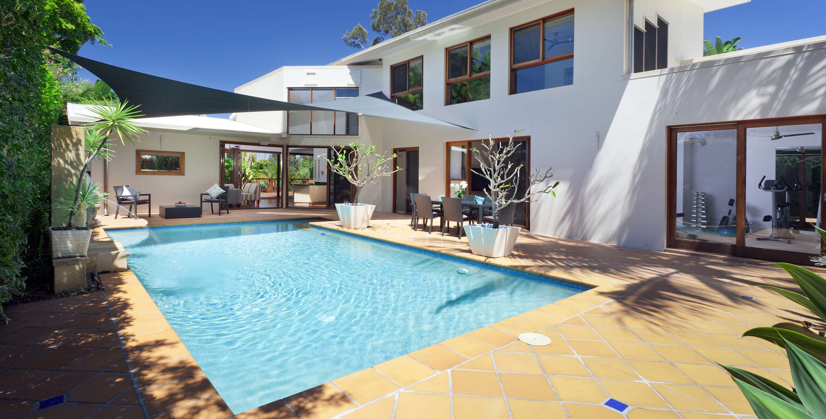 A beautiful pool in the backyard of a modern white home.
