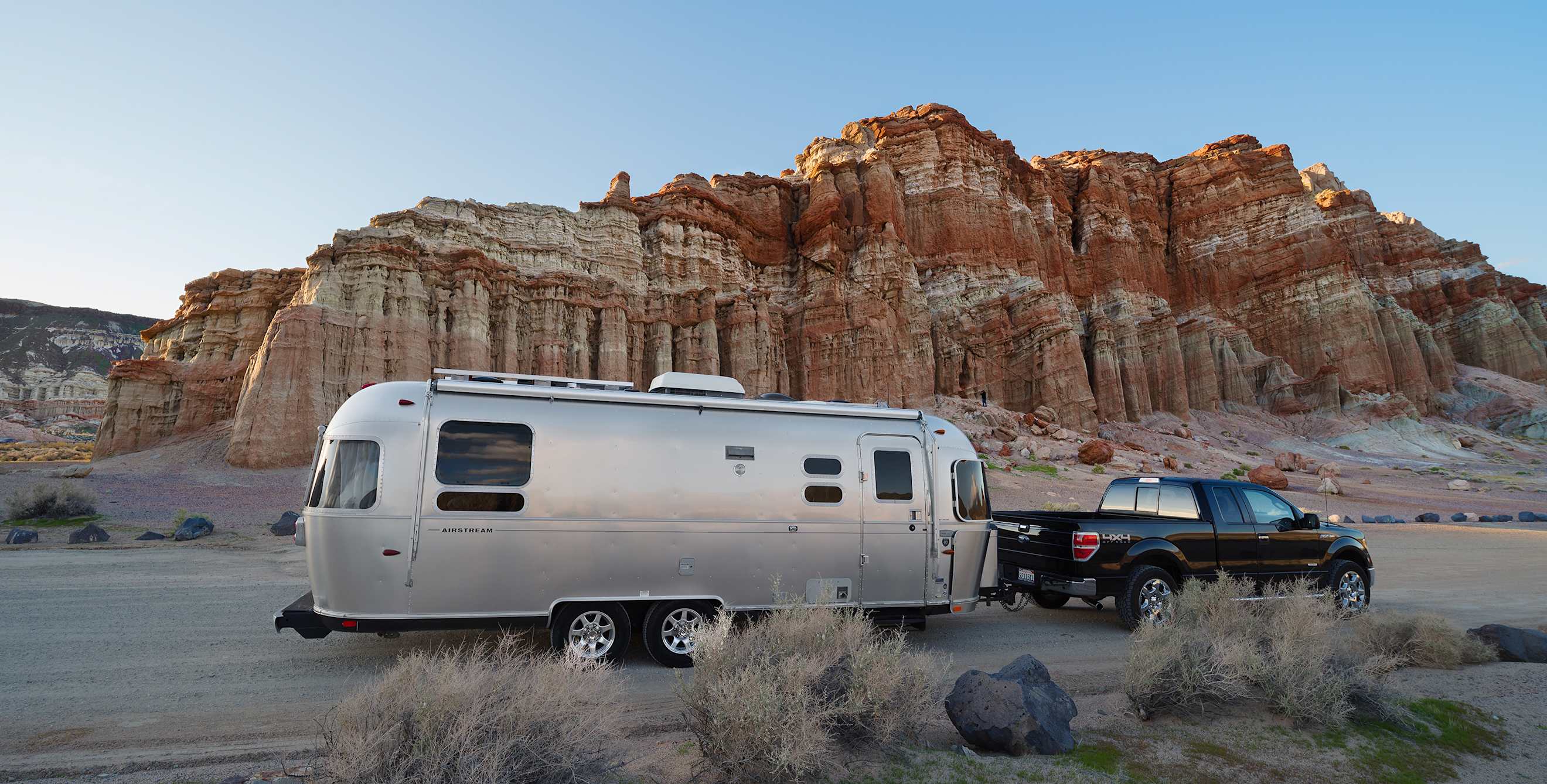 A truck pulls an Airstream trailer through Red Rock Canyon State Park in California.