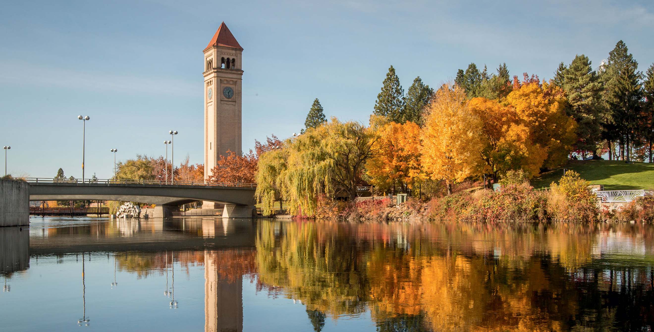 The Great Northern Clocktower and trees with yellow and orange leaves reflect off the Spokane River.