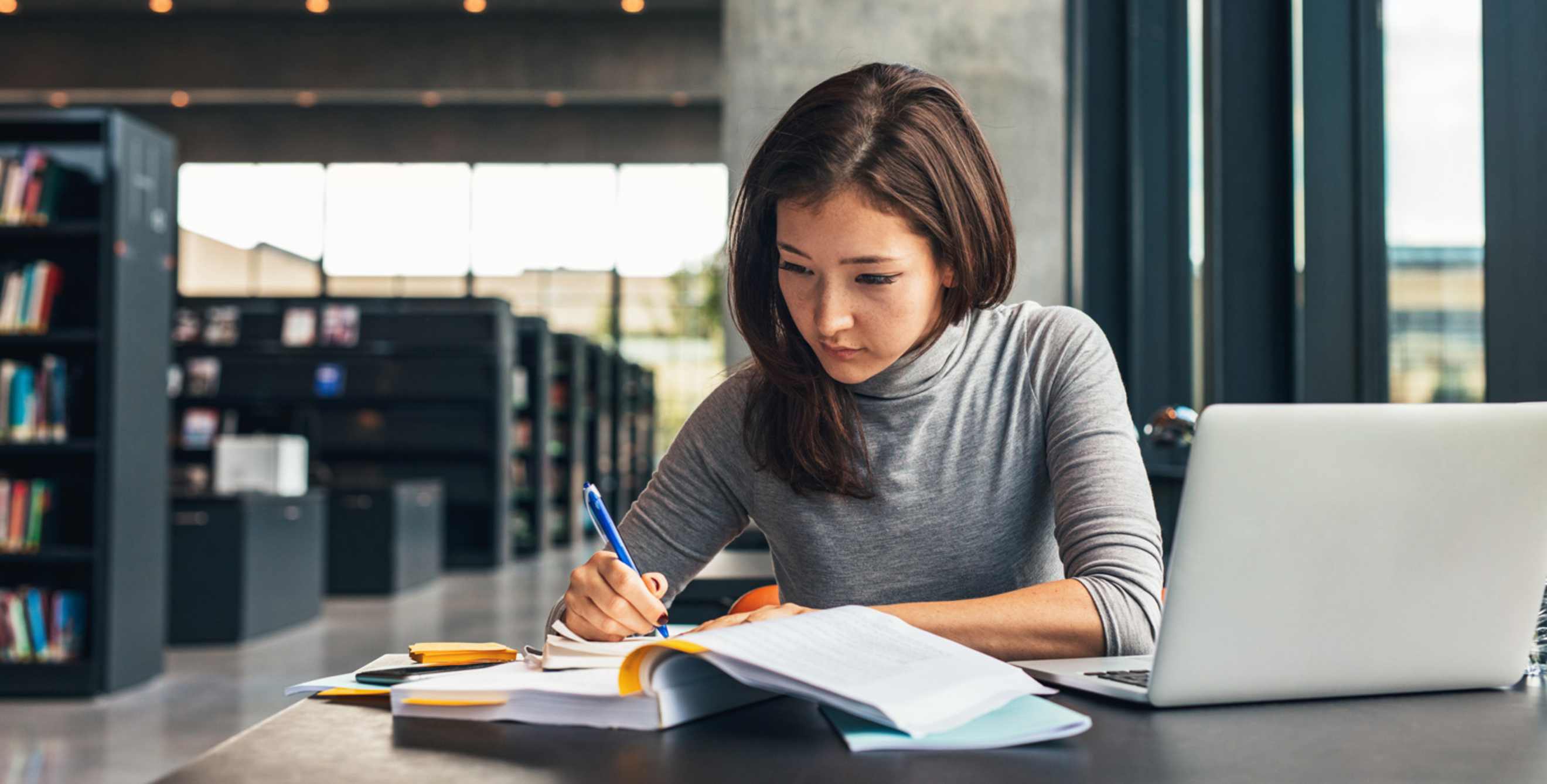 A college student does homework in the library on campus.