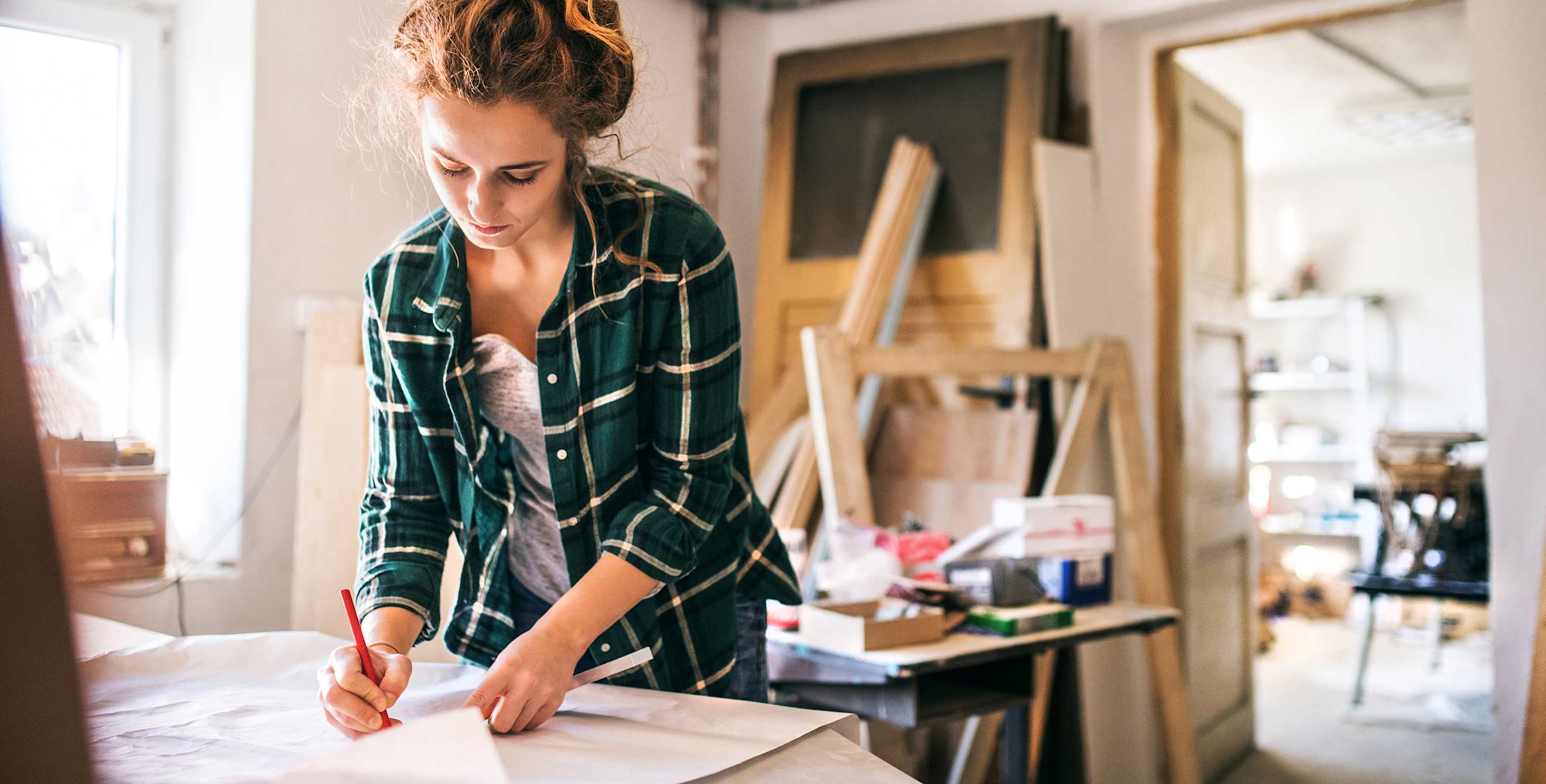 A woman sketches on a building plan.