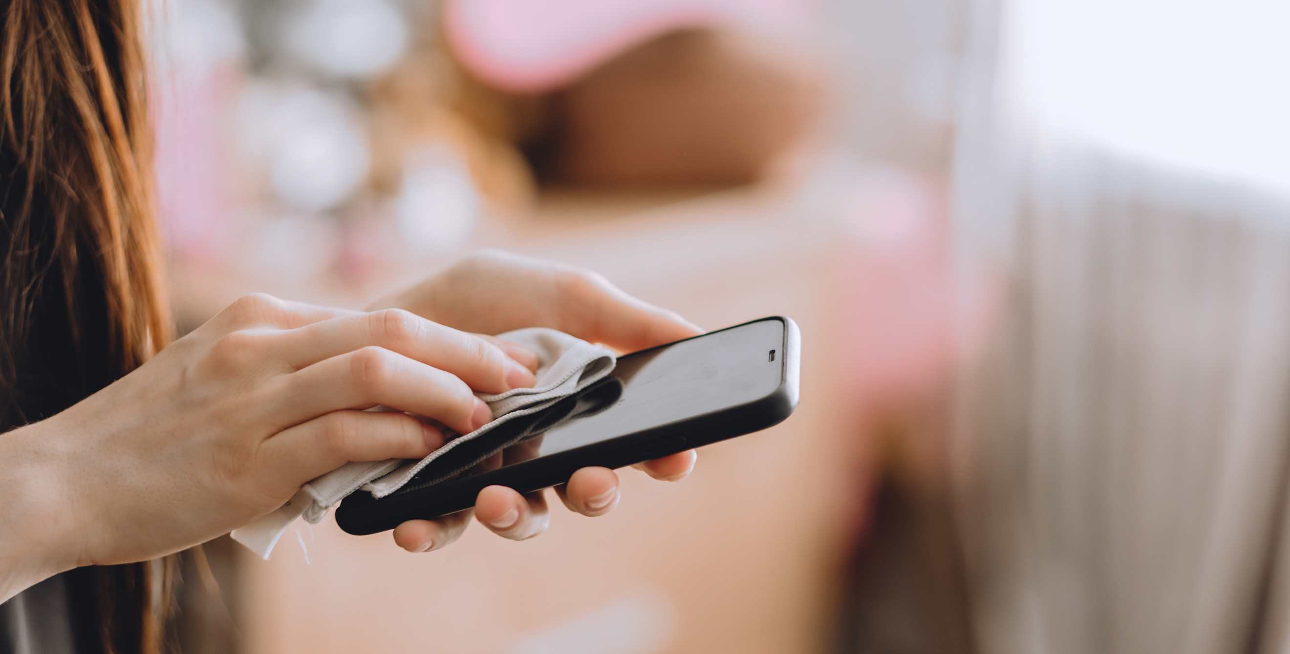 A woman cleans her cellphone with a dry cloth.
