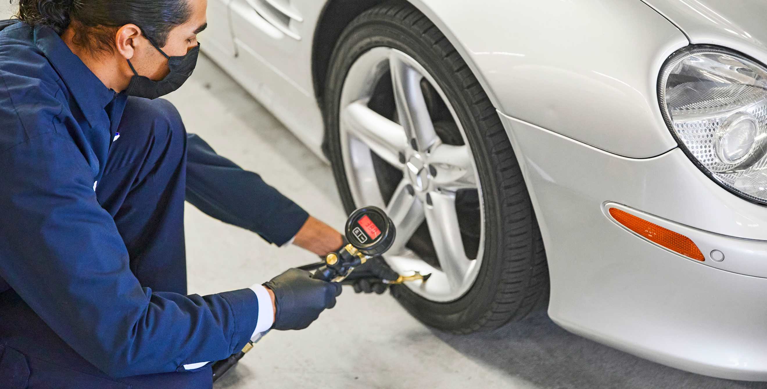AAA Repair Center mechanic uses a tire pressure gauage to check a car's tire pressure.
