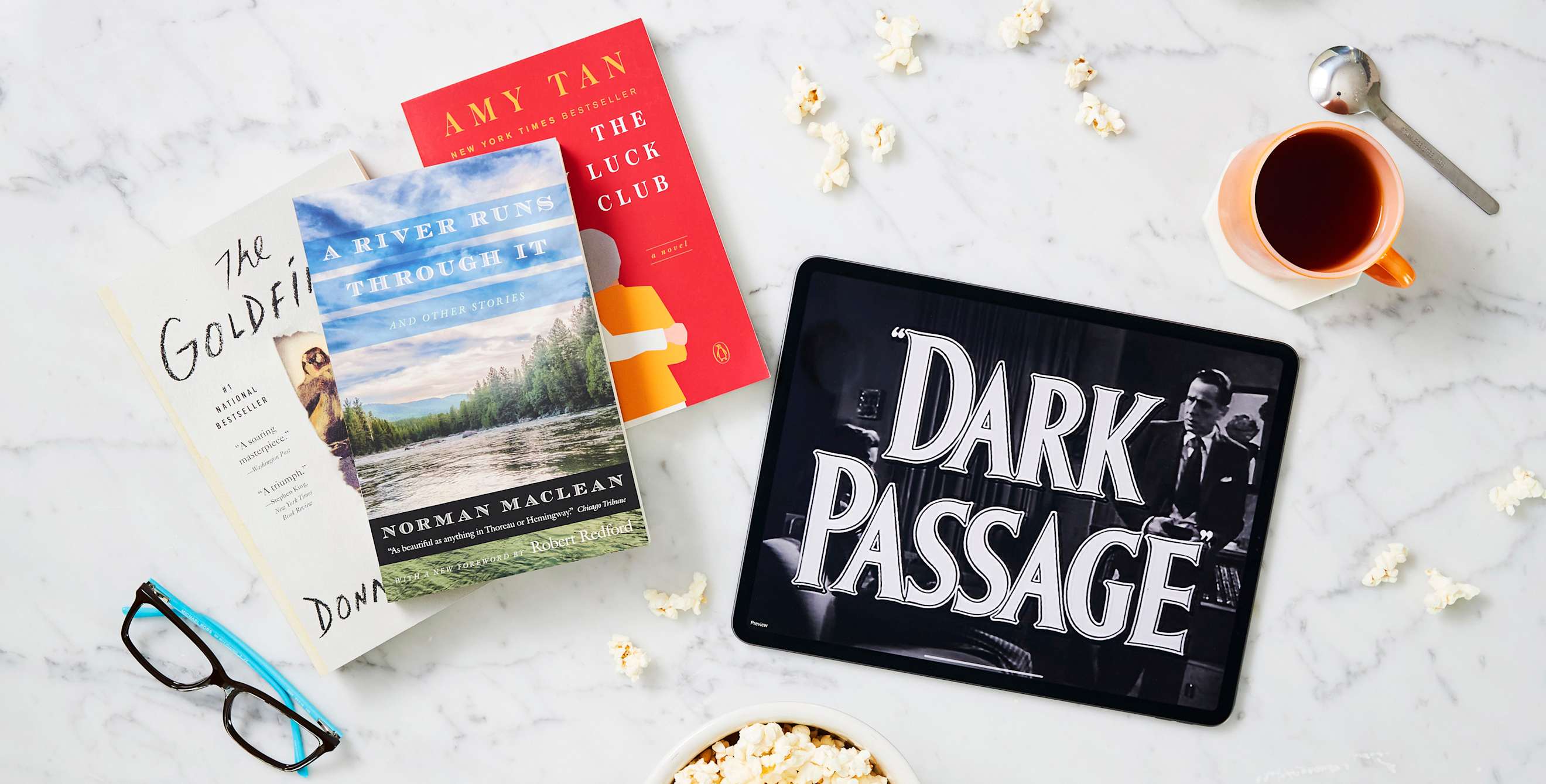 Books and a tablet playing a movie set on a counter.