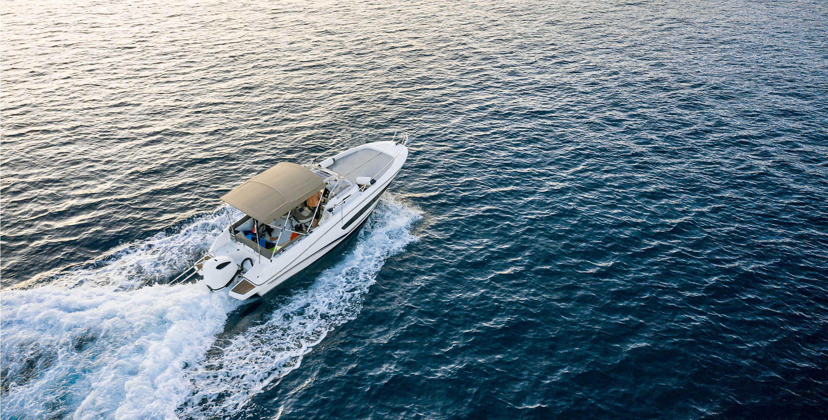 A passenger boat cuts through deep blue water.