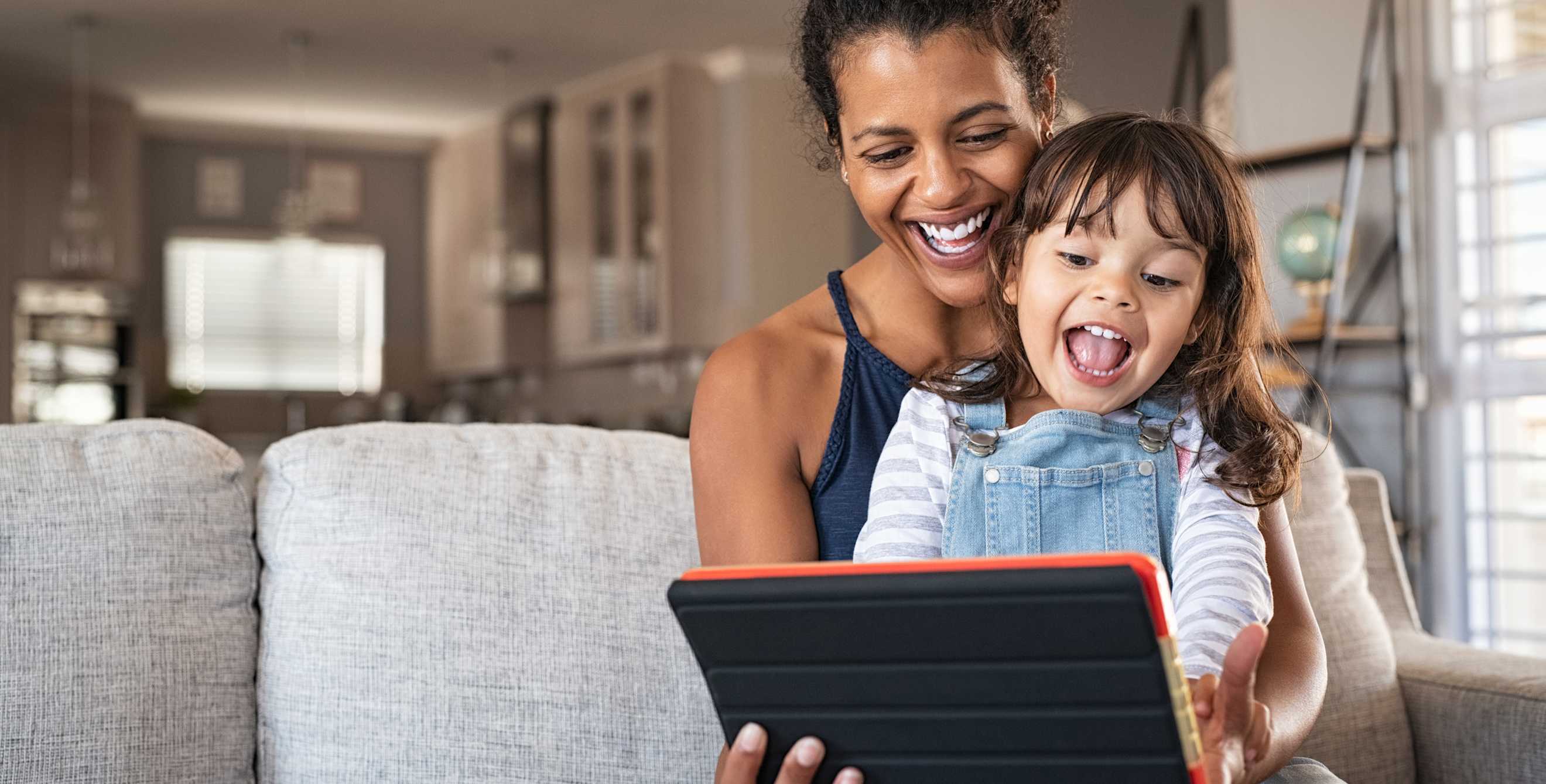 A mom and her child play together on a tablet.