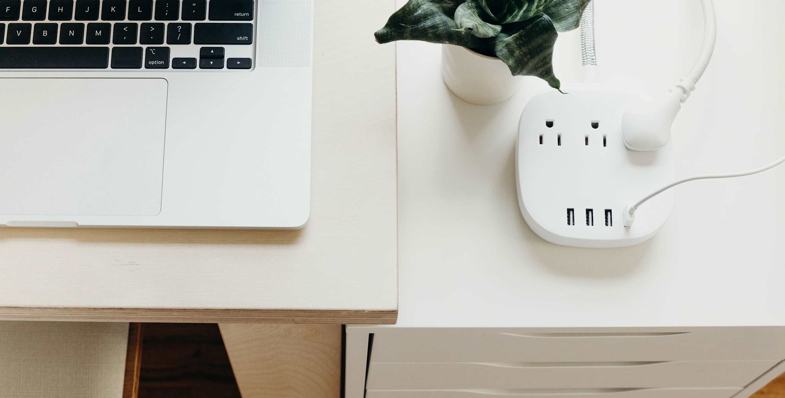 A laptop and a power strip on a desk.