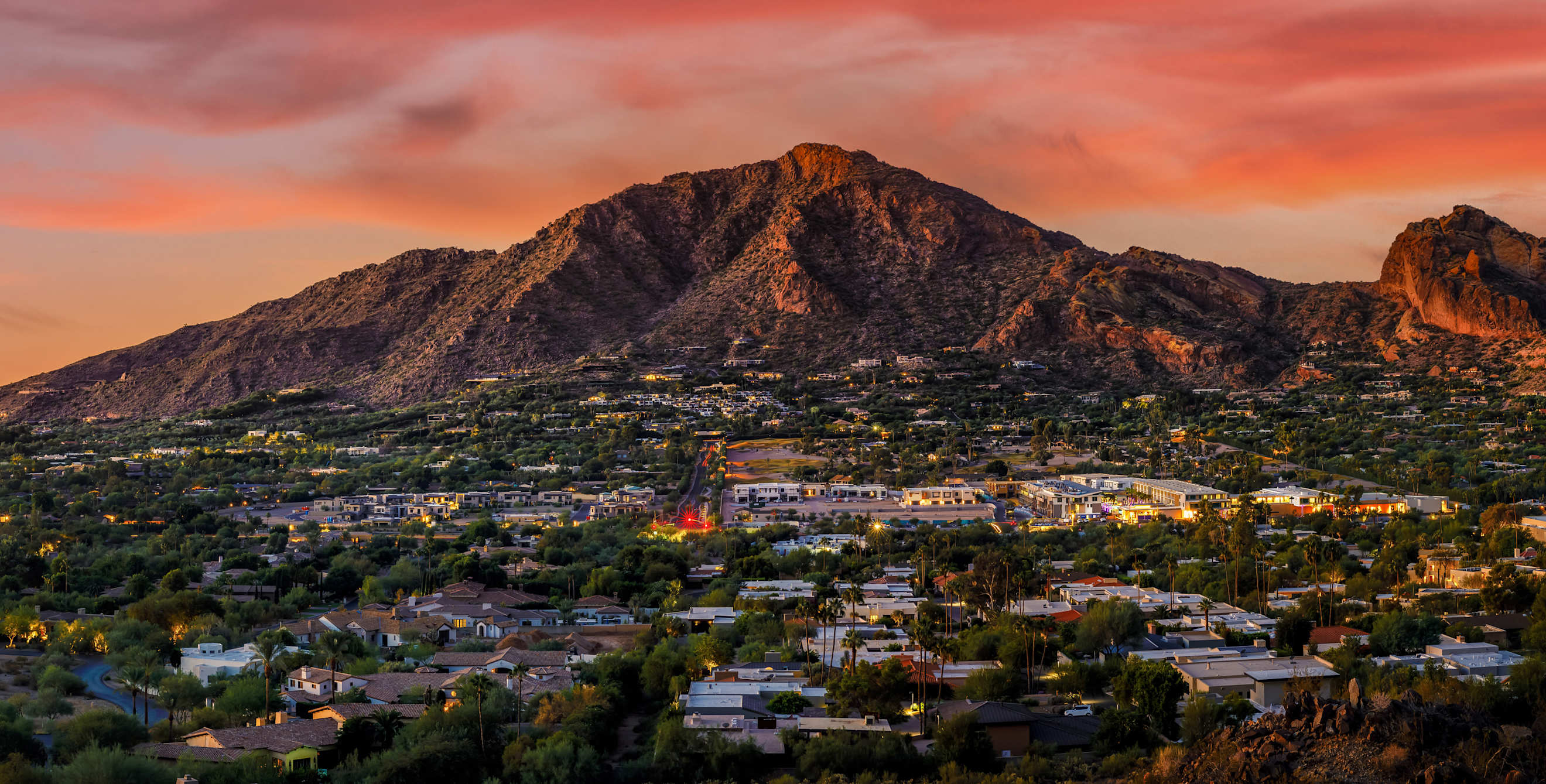 Clouds glow orange over Camelback Mountain in Phoenix, Arizona at sunset.