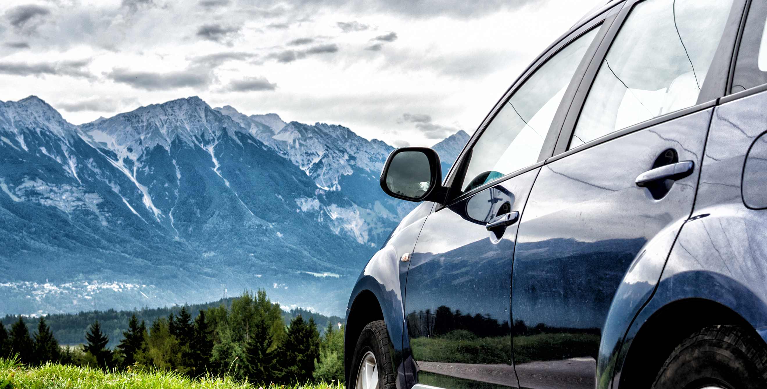 A small car parked at a mountain overlook.