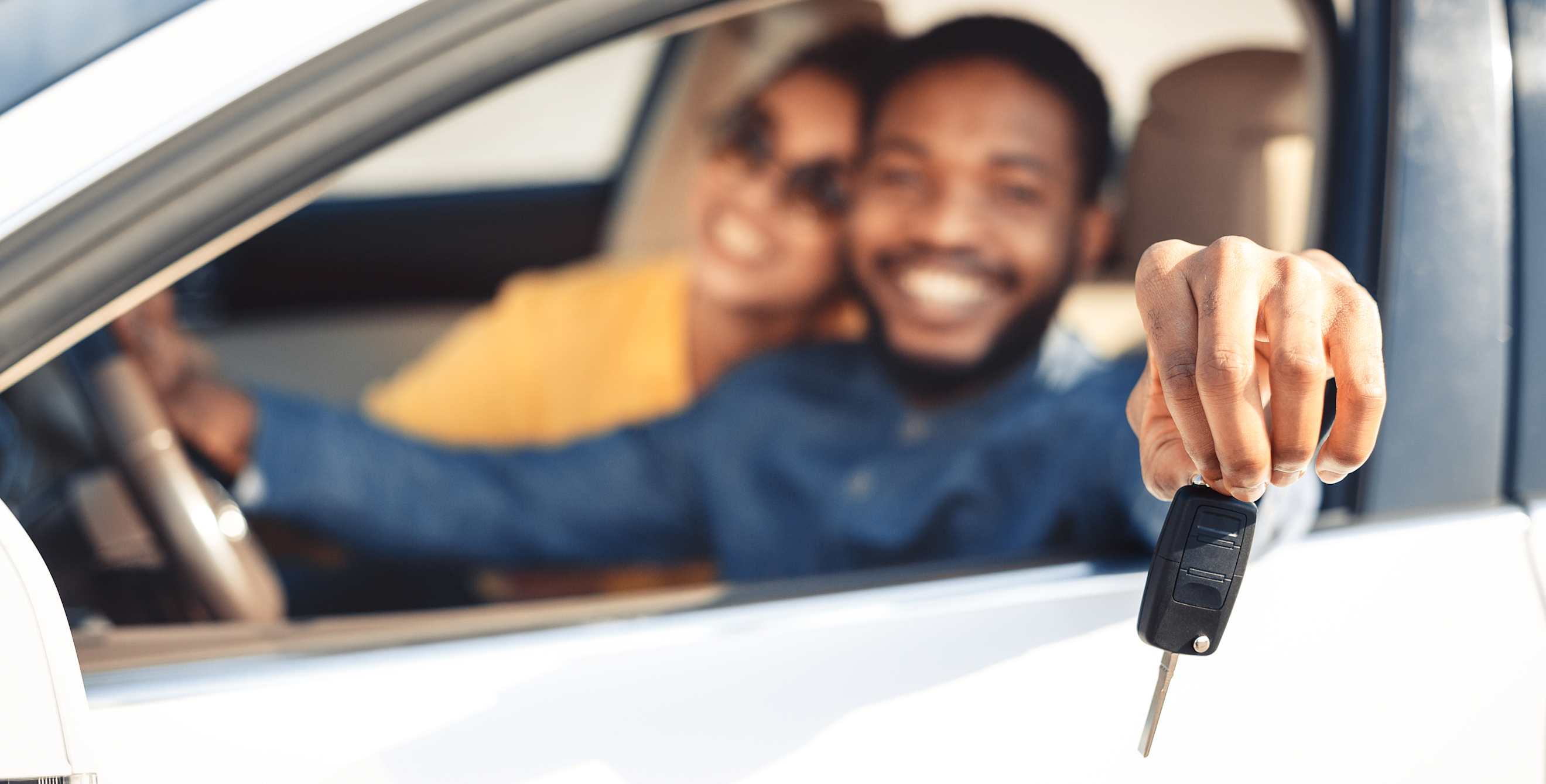 A couple hold the keys to their new sedan.
