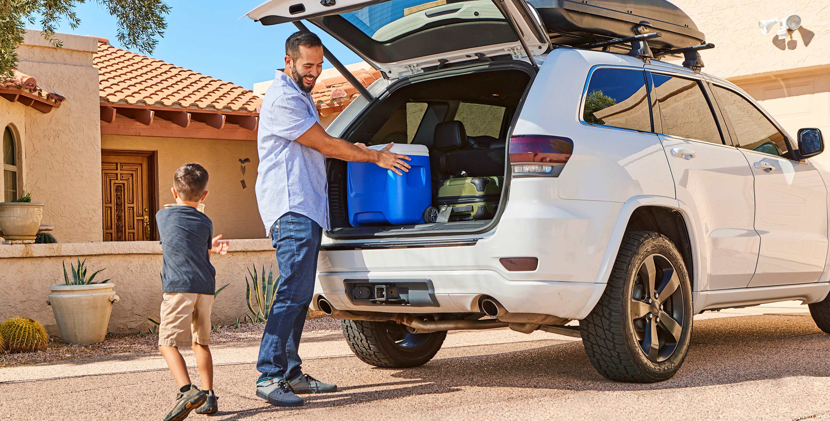 A father and son put a cooler into the back of an SUV.
