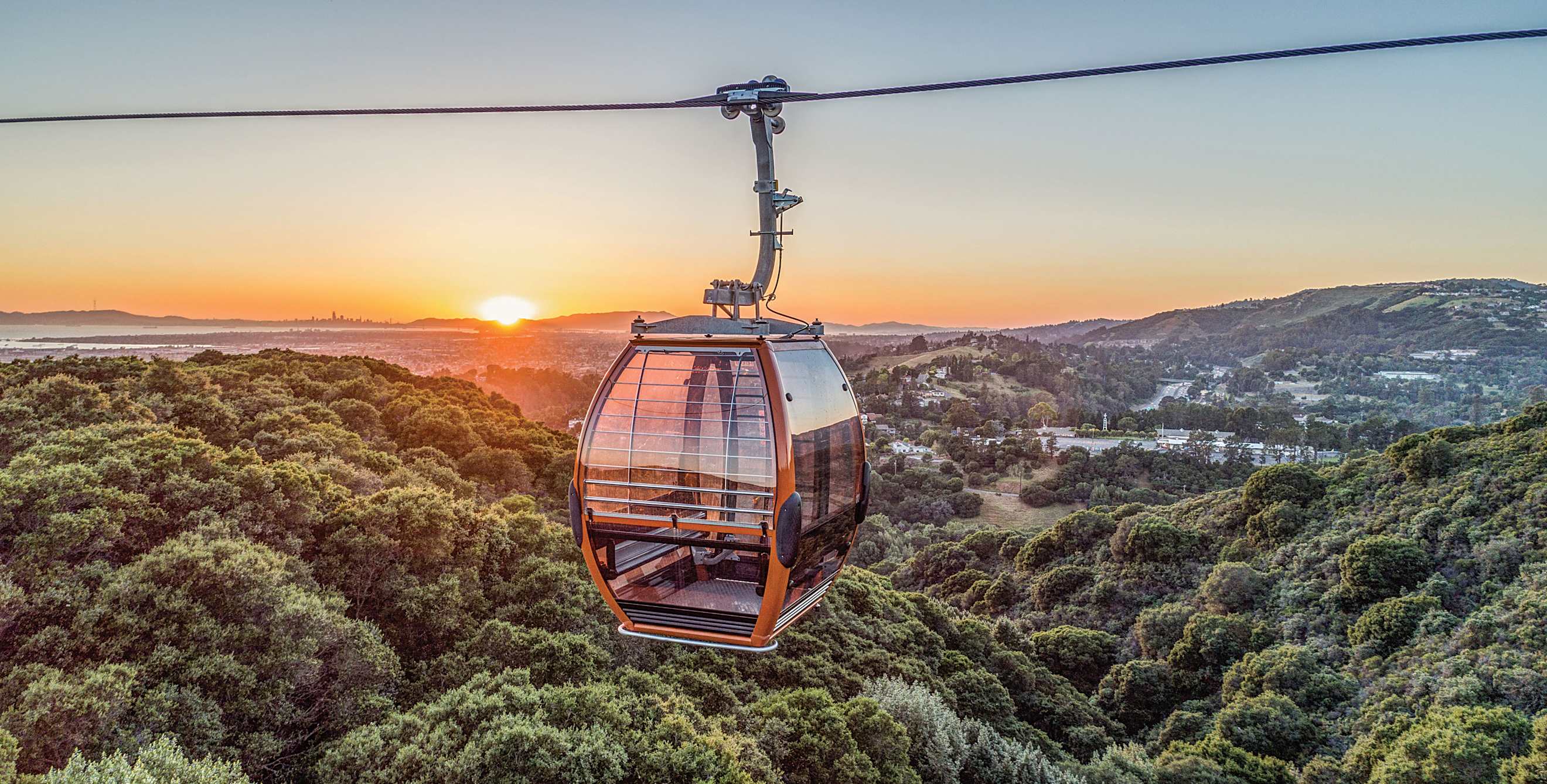 Oakland Zoo Gondola with the Oakland Hills and a sunset in the background.