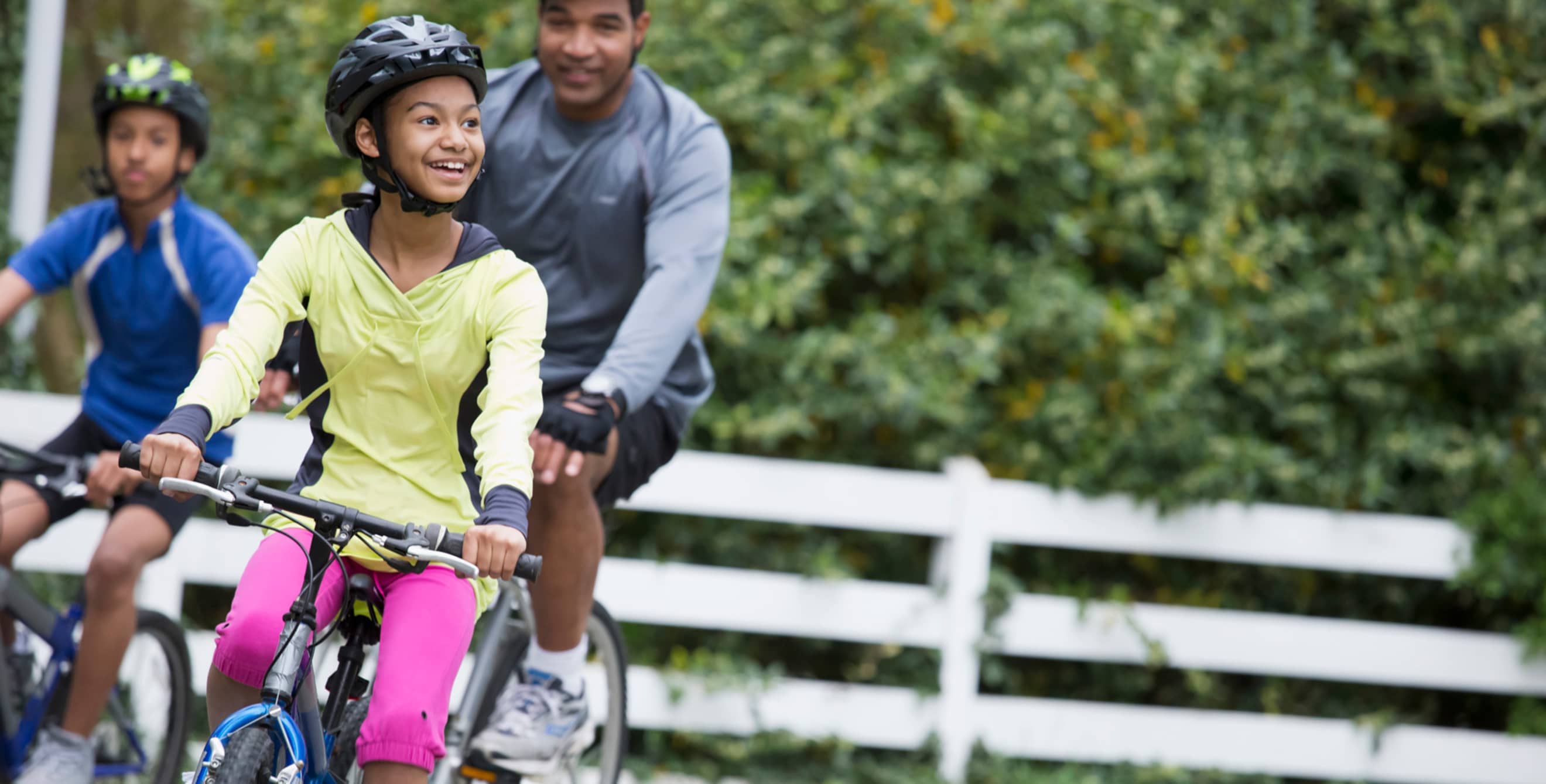 family of three ride bicycles wearing helmets, picture