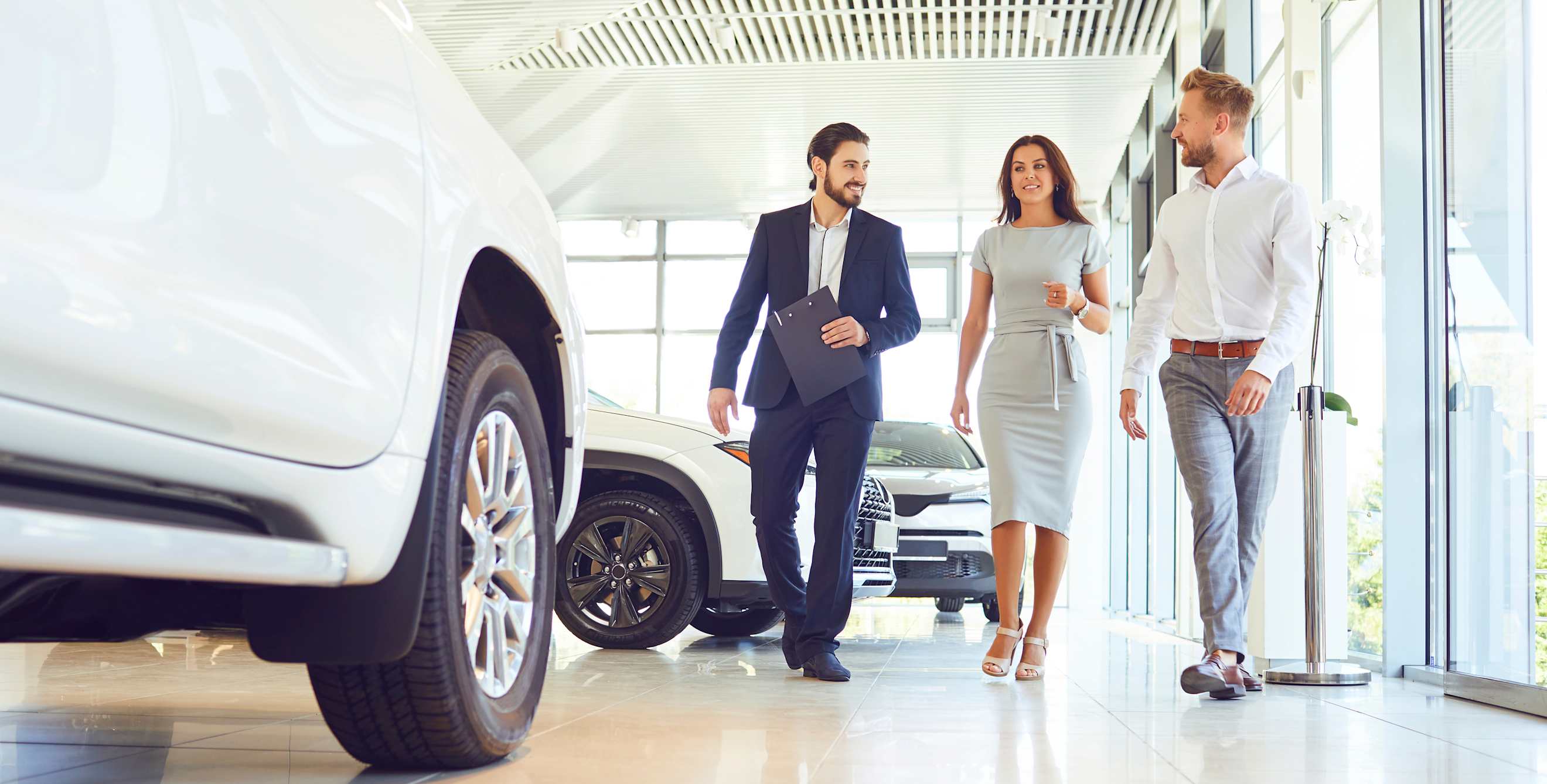 A couple walk through a car dealership with a sales person