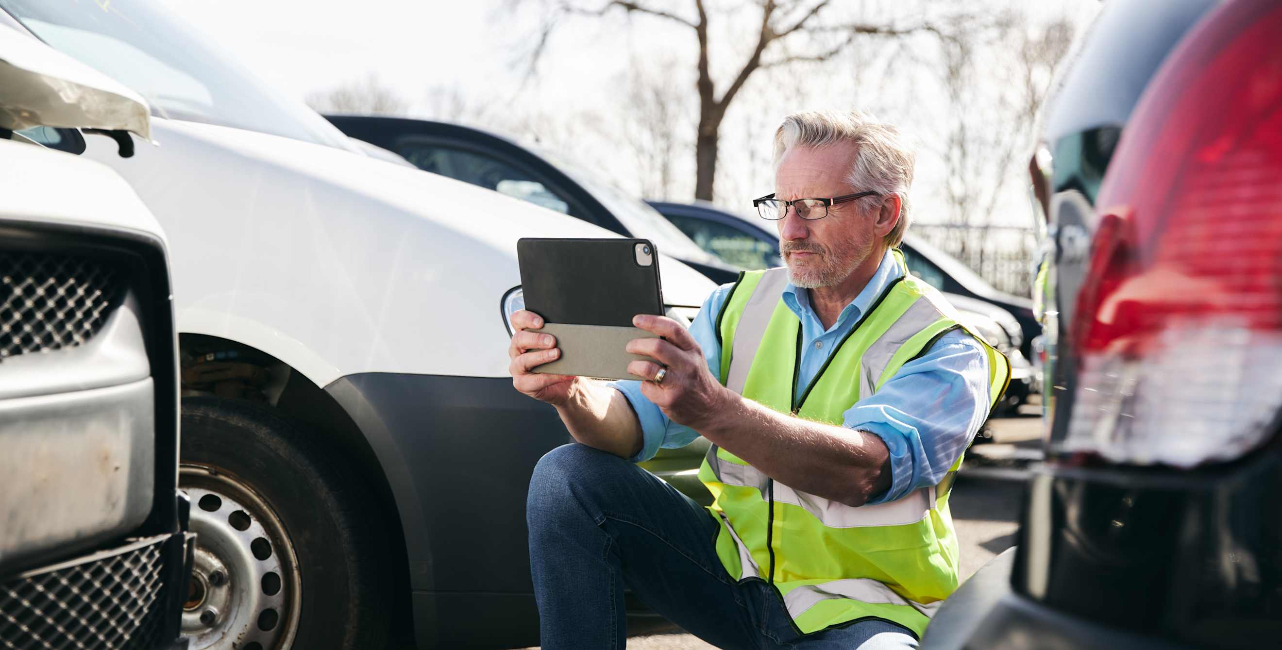 A claims adjuster takes picture of a damaged car.