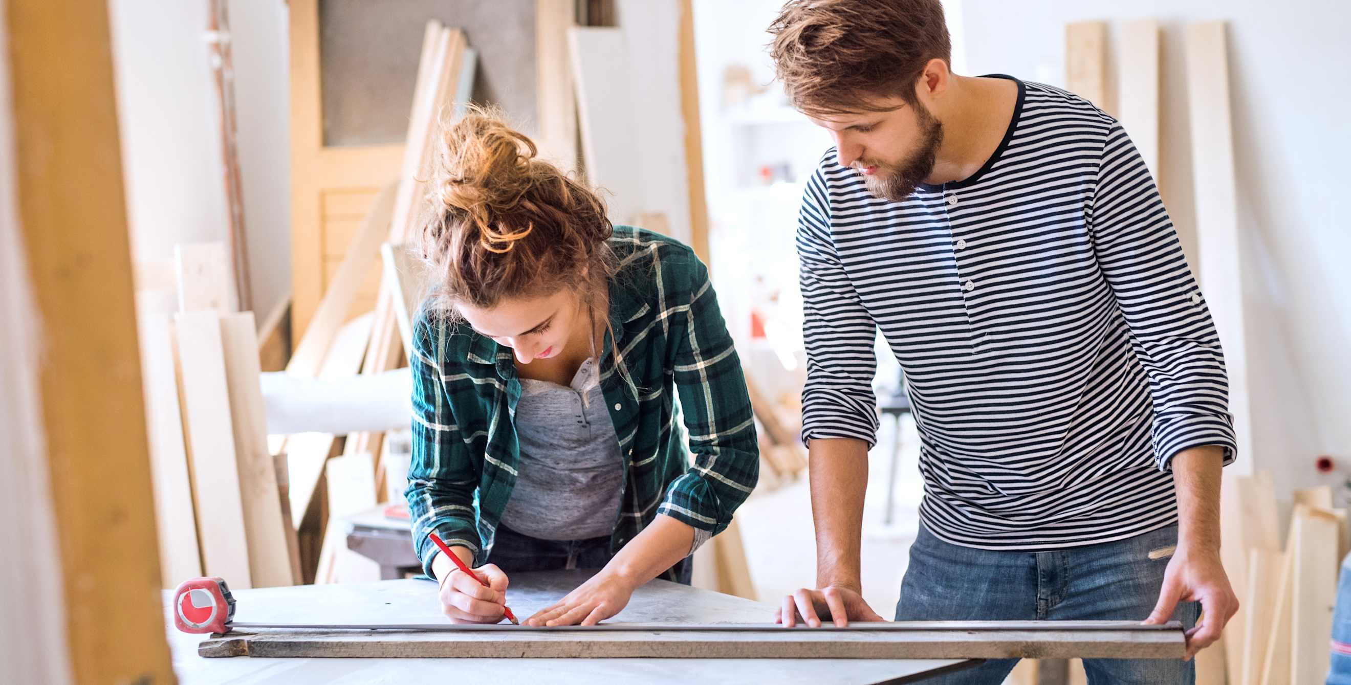A couple cuts a piece of trim while remodeling their home.