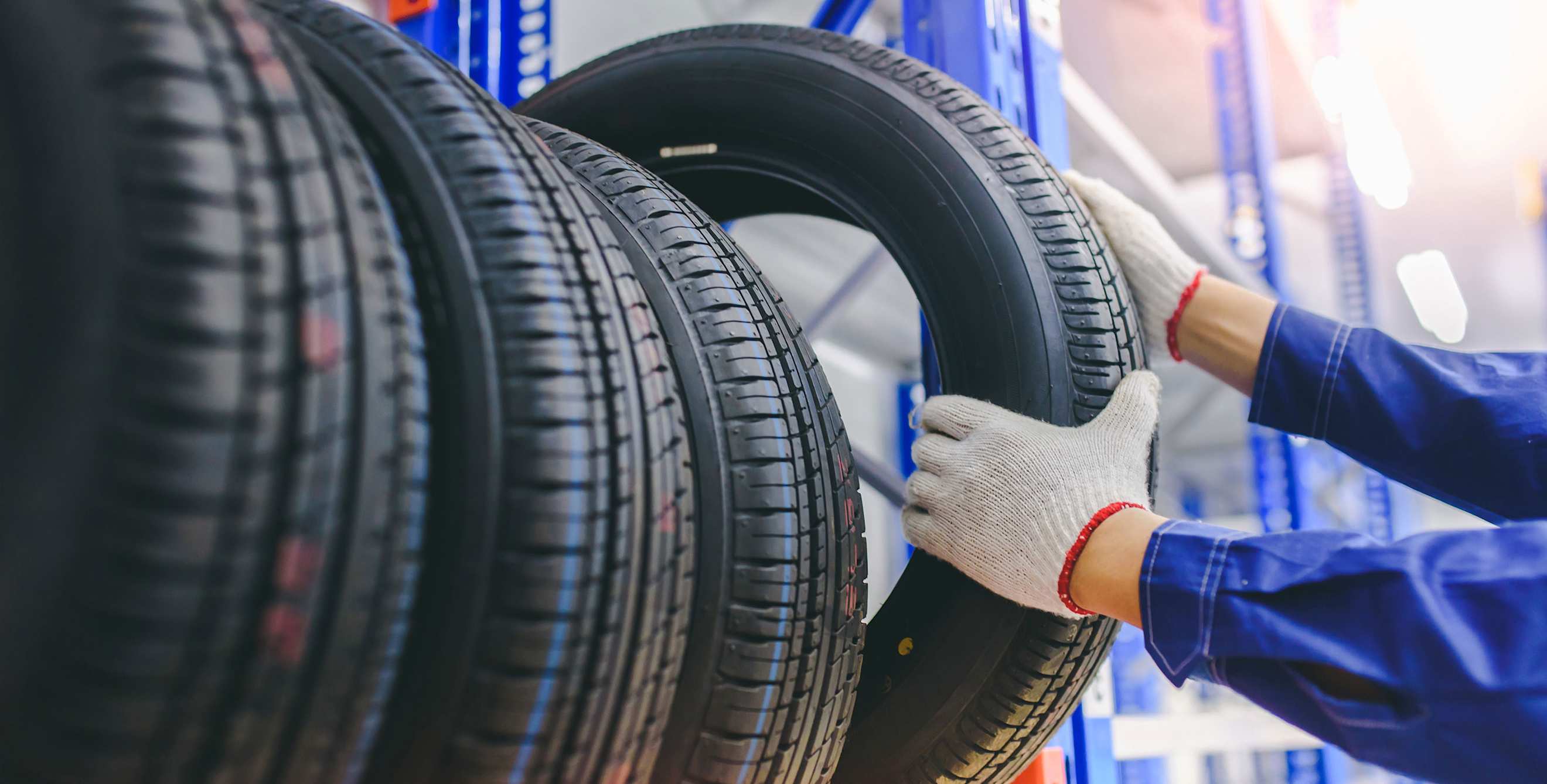 A mechanic pulls a tire off a rack.