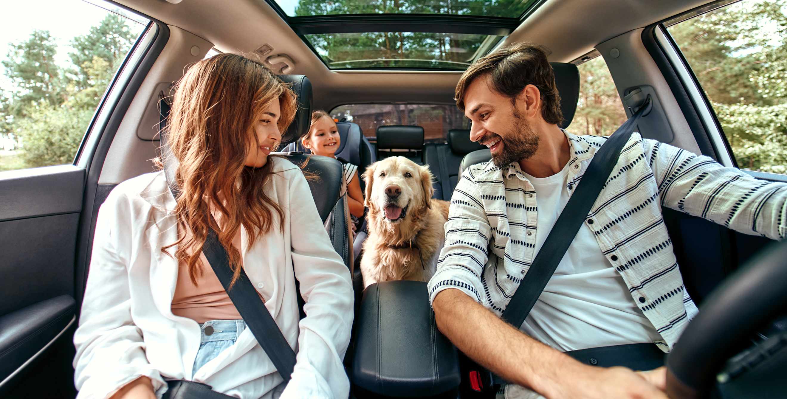 A family and their dog are buckled up inside an SUV.