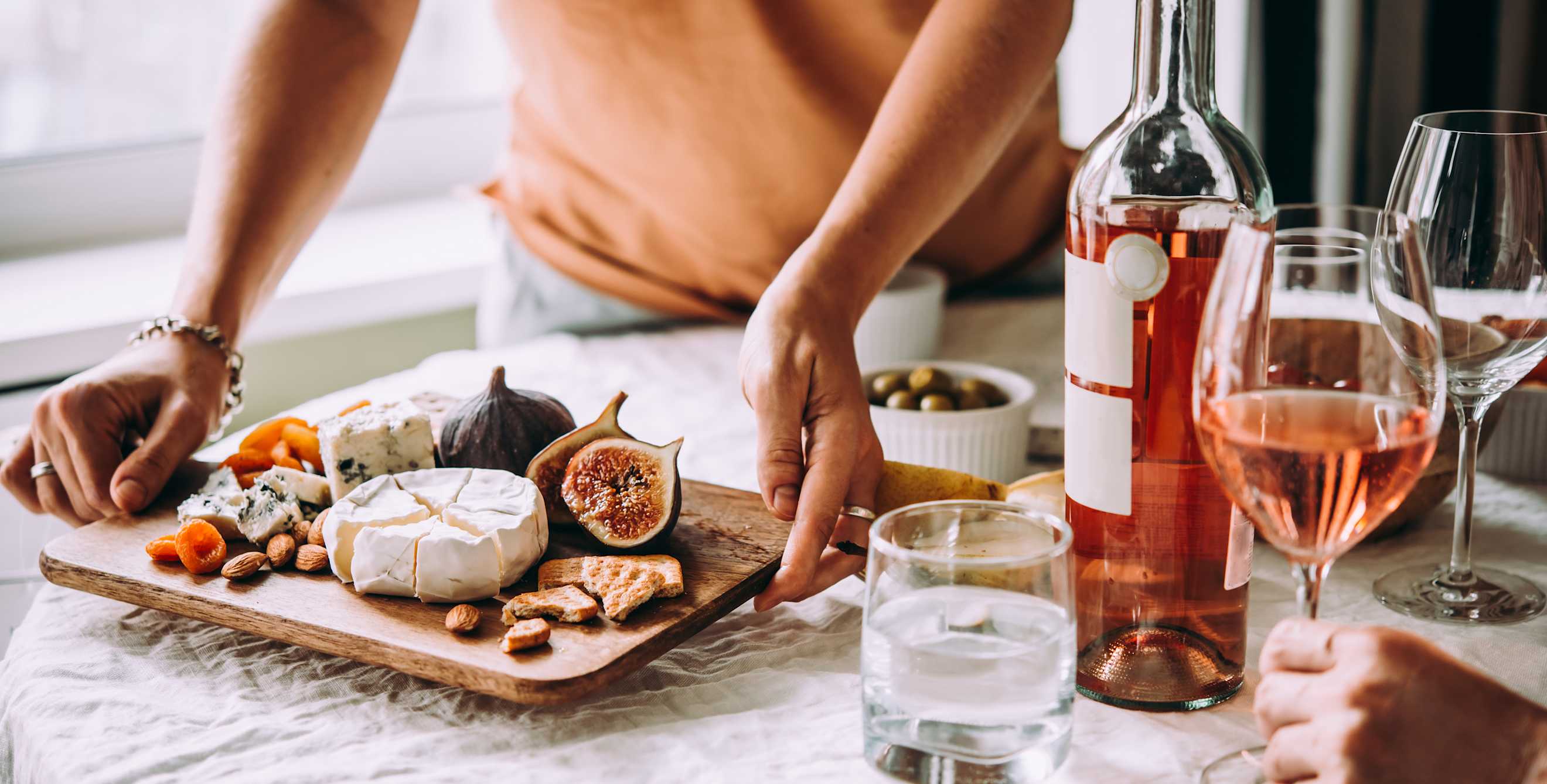 A host puts a fruit and cheese platter onto the table.