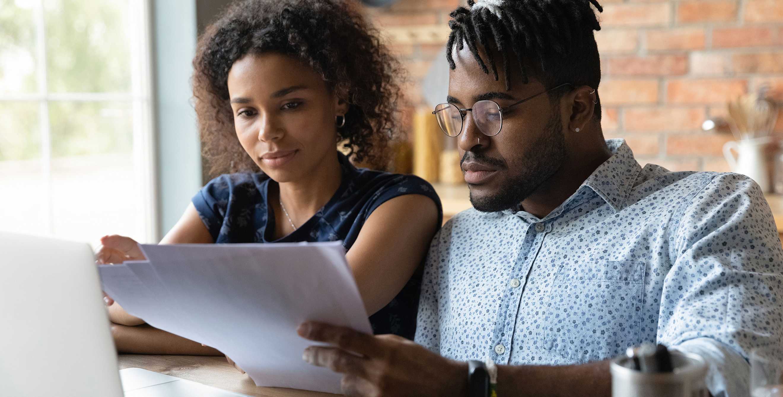 a couple go over the finances together at the kitchen table.