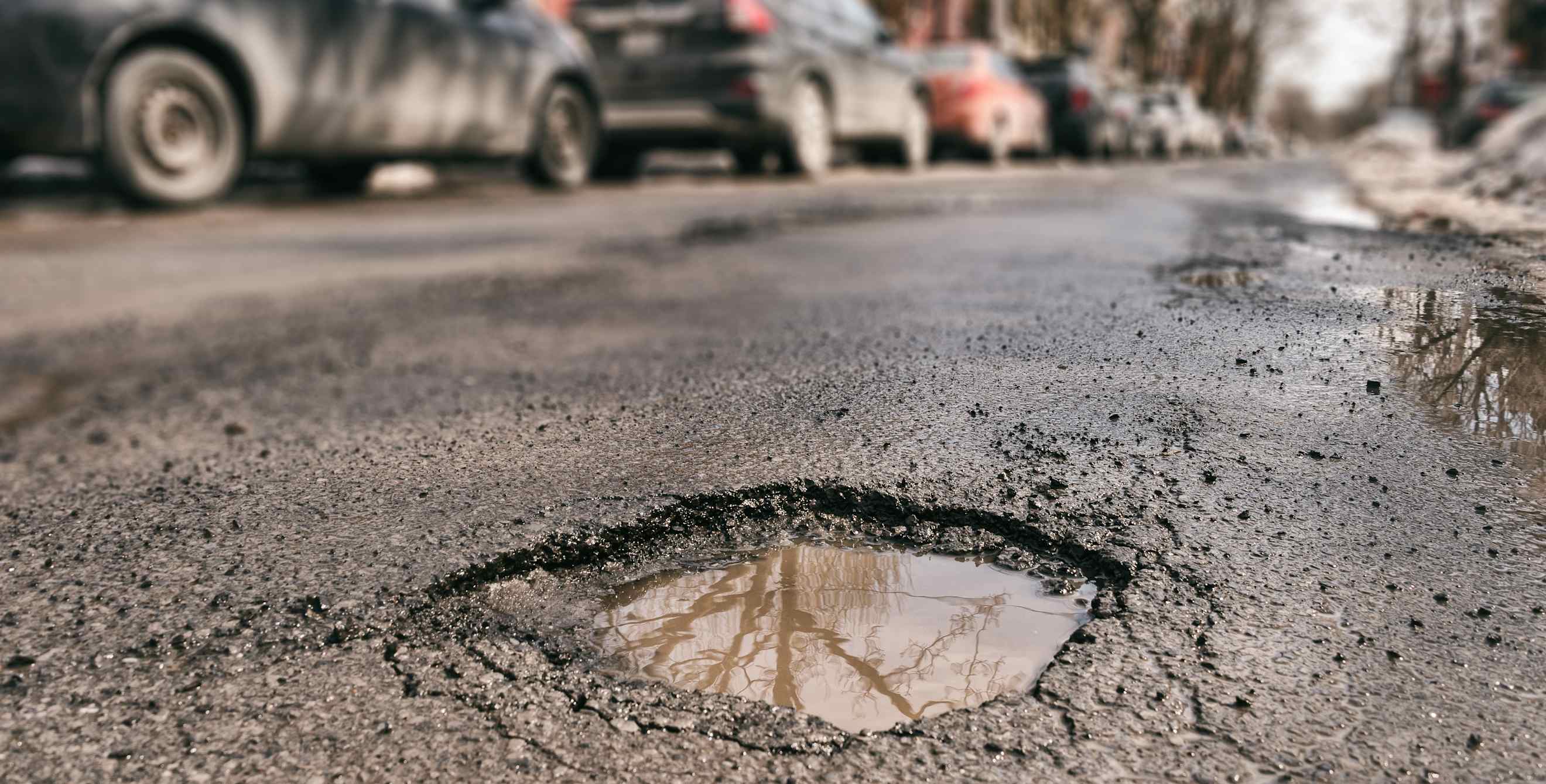 A pothole reflects the sky on a winter road.