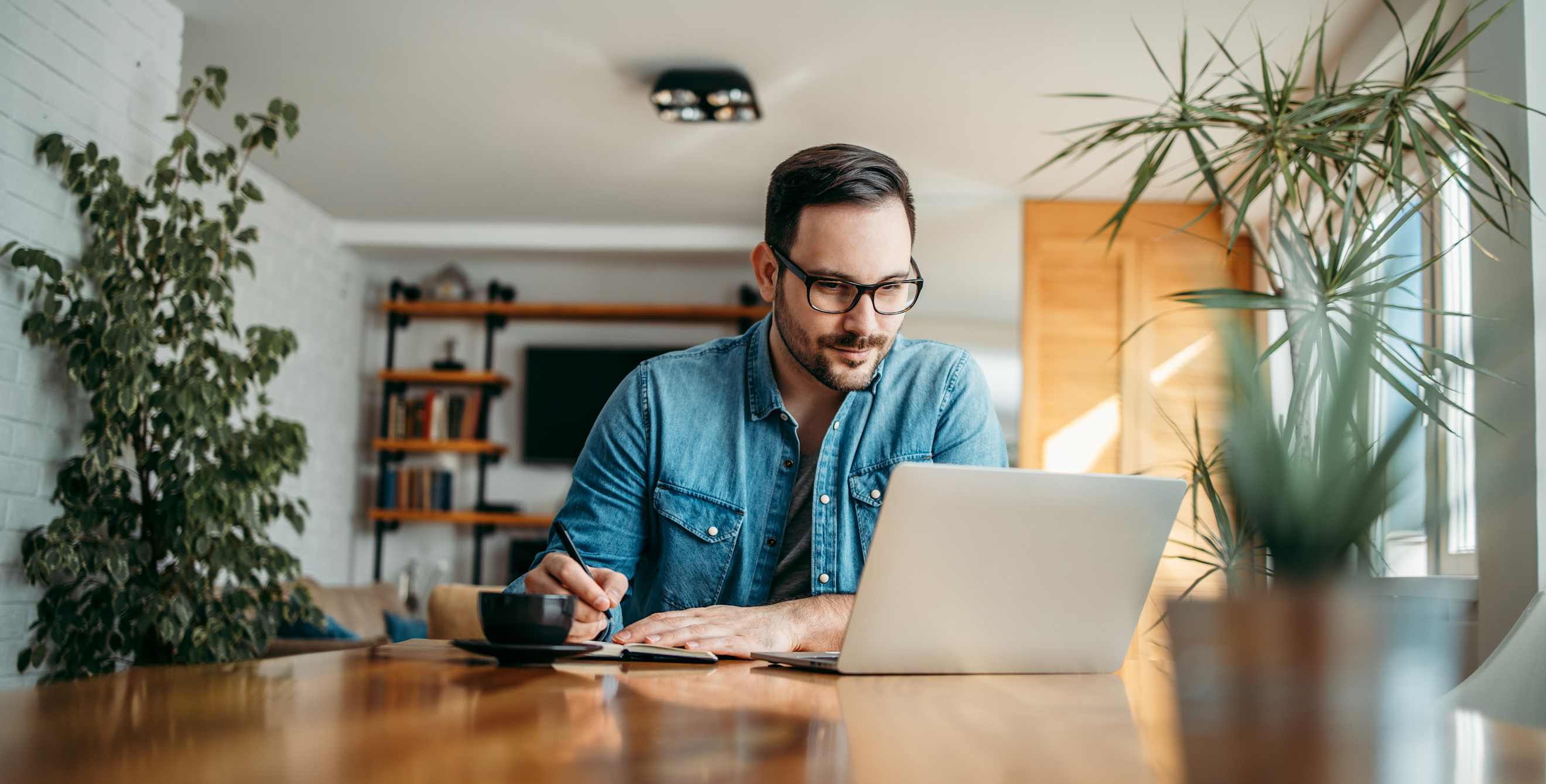 A man looks at his computer at the dinner table.