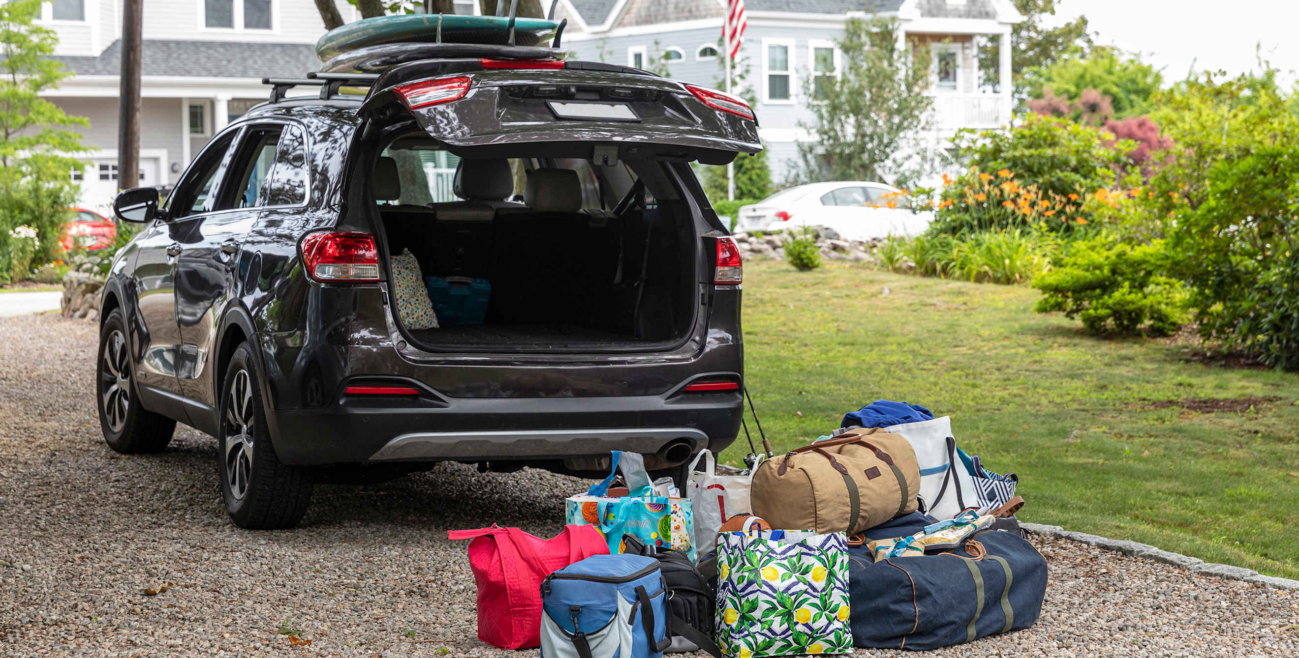 Bags are piled up behind an SUV to be loaded into the car before a road trip.