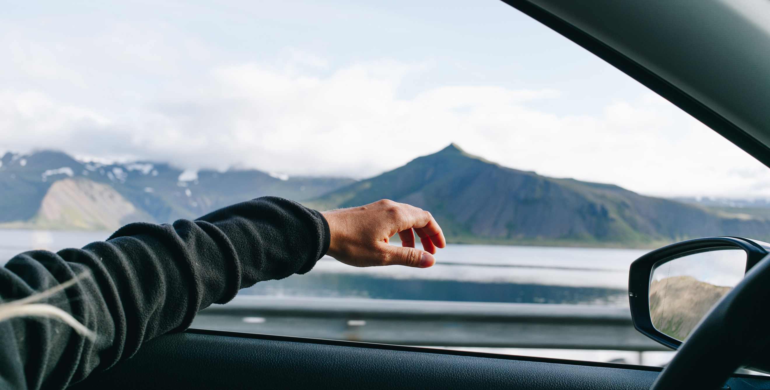 A person drives with their left hand out the window