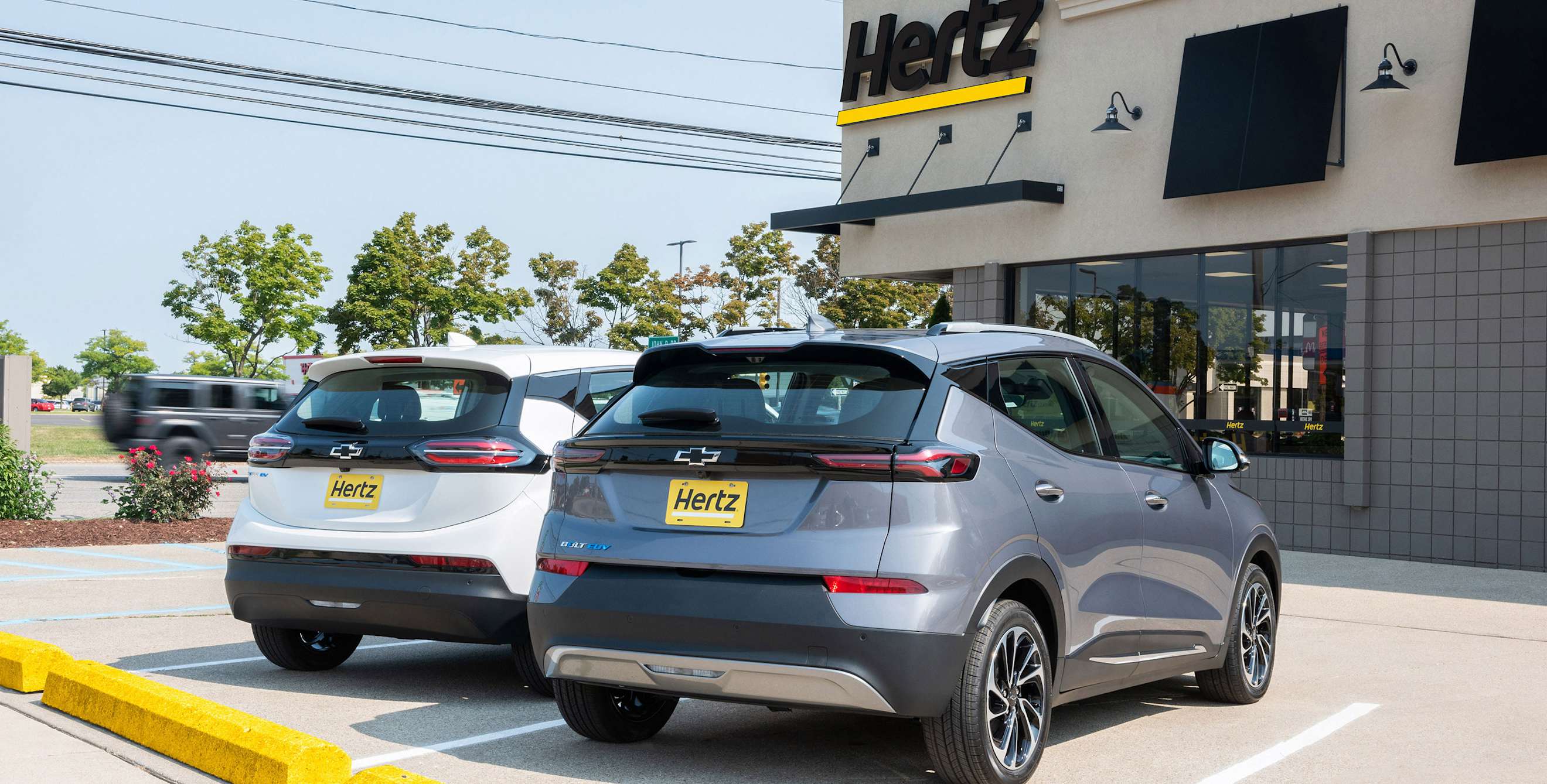 Chevy Bolts outside of a Hertz car rental building.