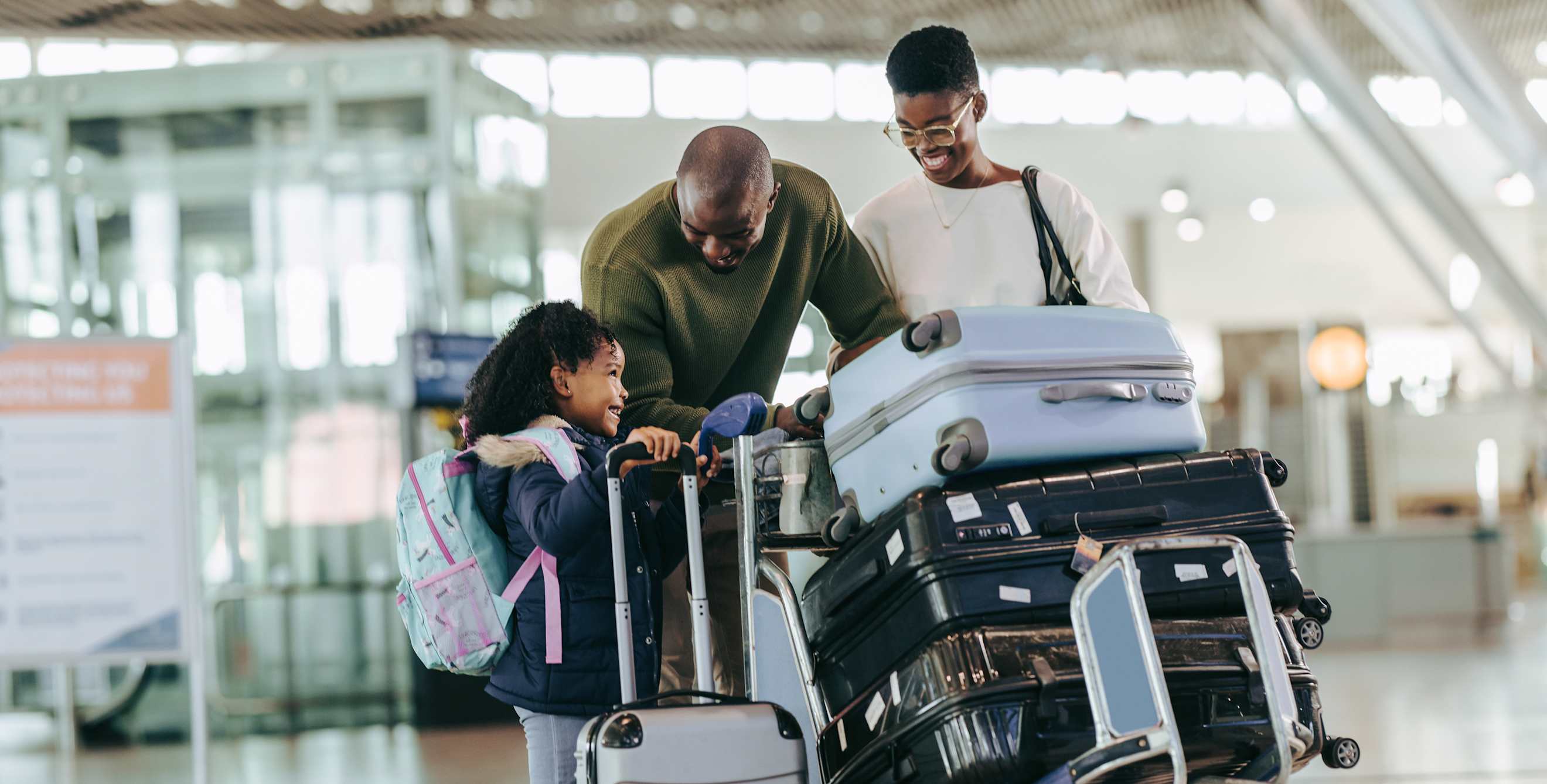 A family moves their luggage on a trolley inside an airport.