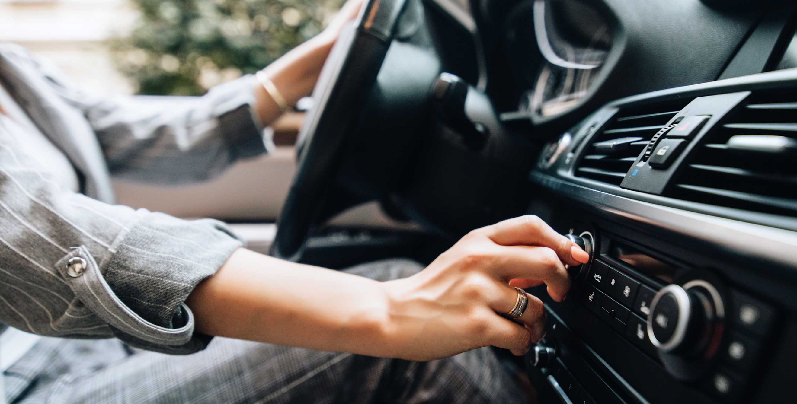 A driver turns on the car's air conditioning on the dashboard.