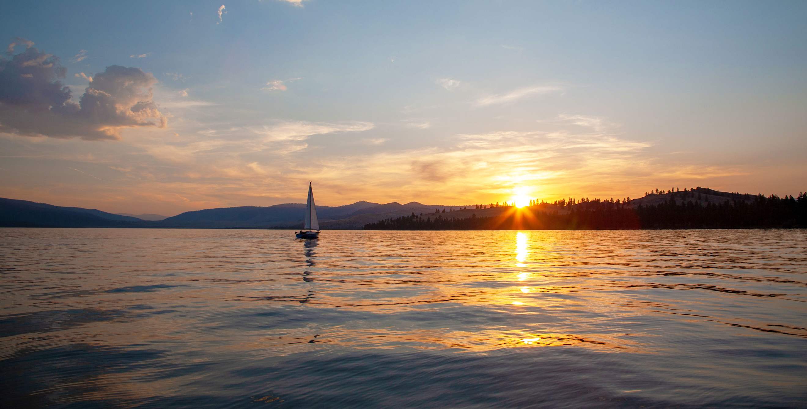 A boat sails at sunrise near Wildhorse Island on Flathead Lake near Kalispell, Montana.