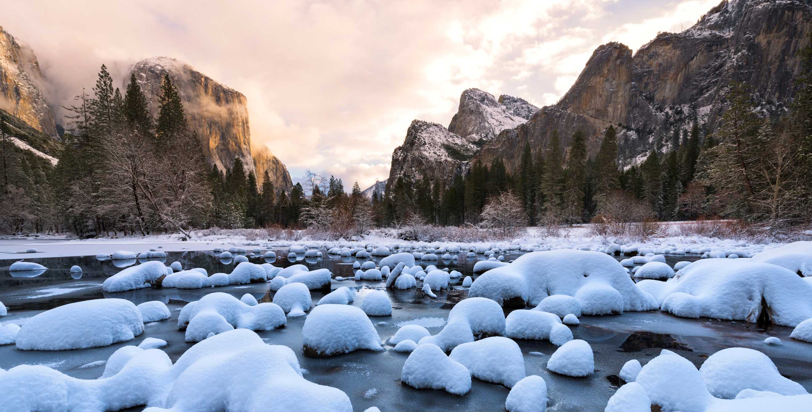 Yosemite Valley at sunrise from Valley View along a frozen Merced River after a winter snow storm.