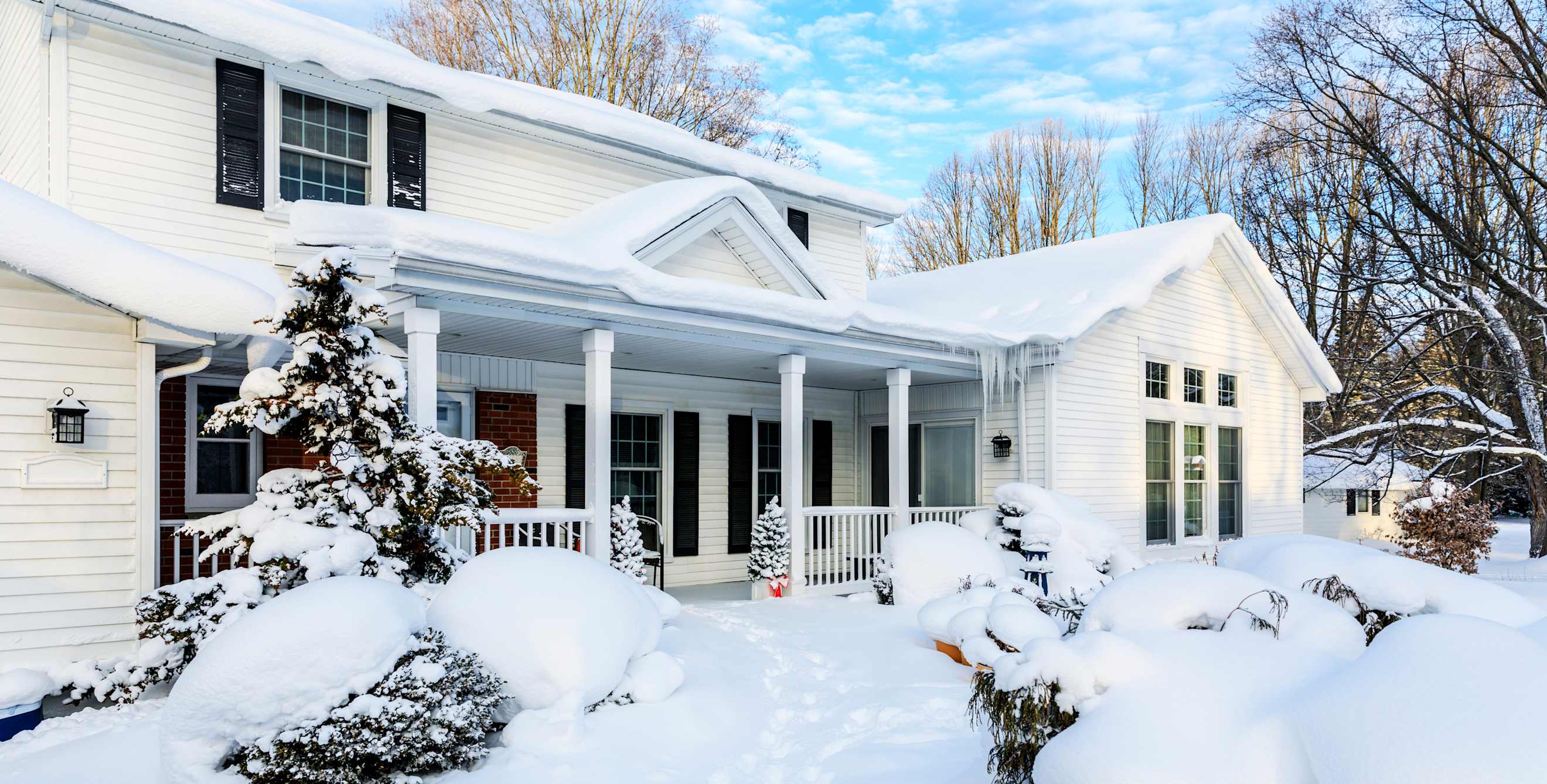 A white house covered in snow and icicles. 