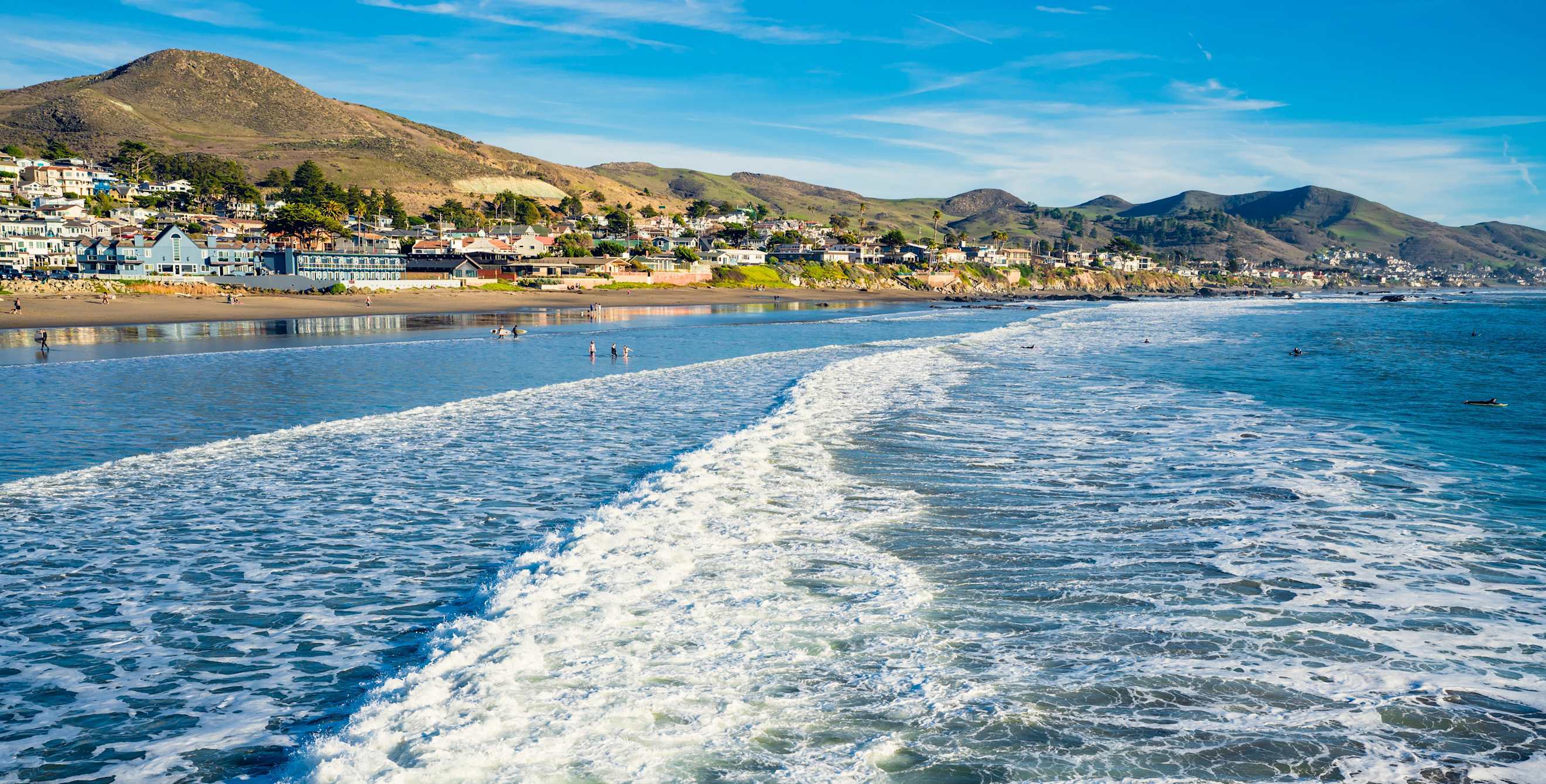 Gentle waves crash onto Cayucos State Beach on the waterfront of Cayucos on the Central Coast of California.
