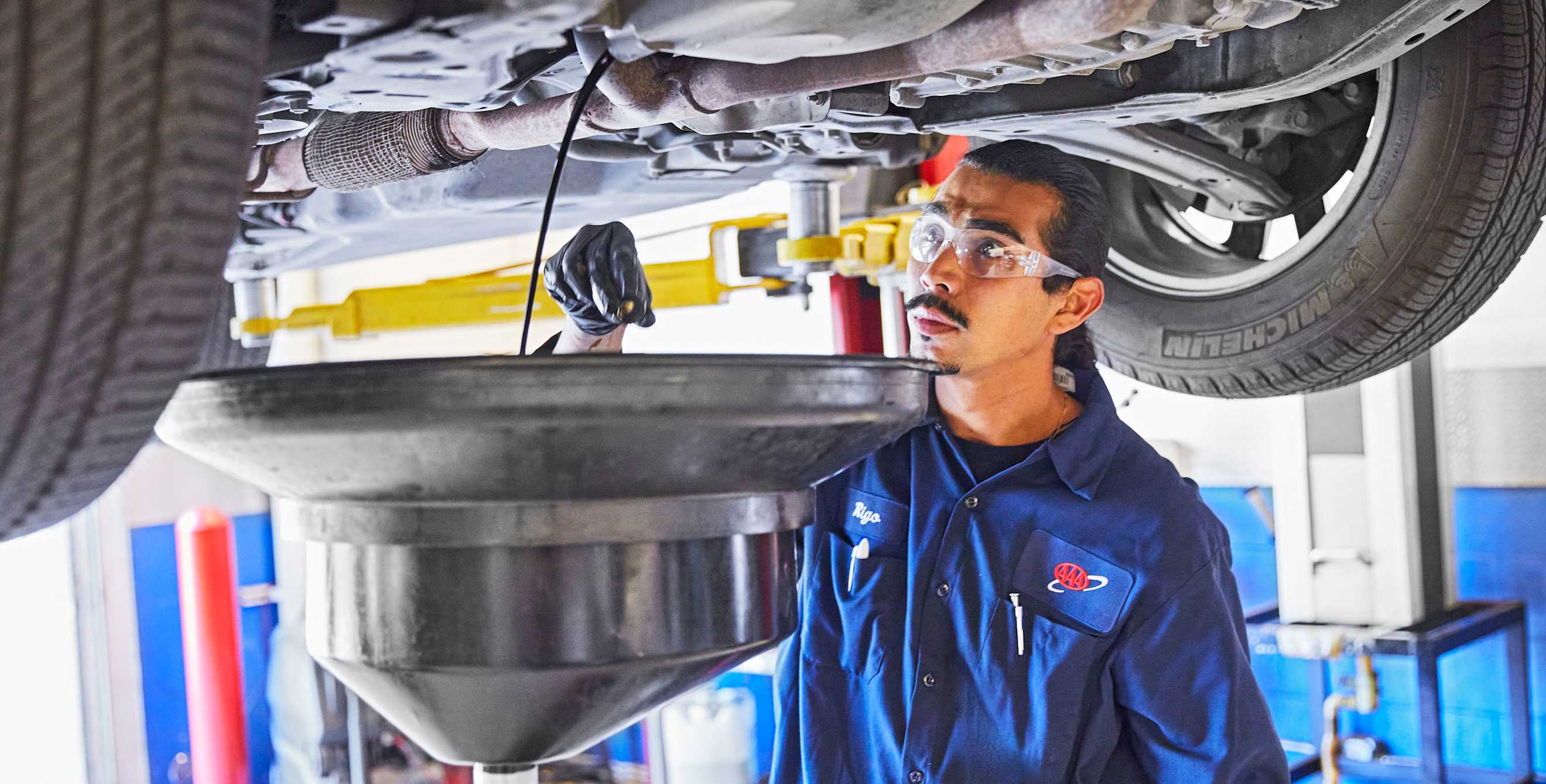AAA auto mechanic drains engine oil.